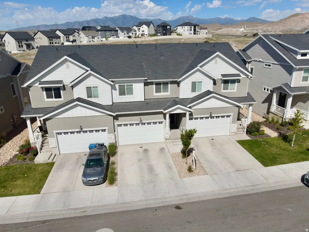 Modern multi-family dwelling featuring a two-tone facade with white trim, dark gray roofing, and attached garages