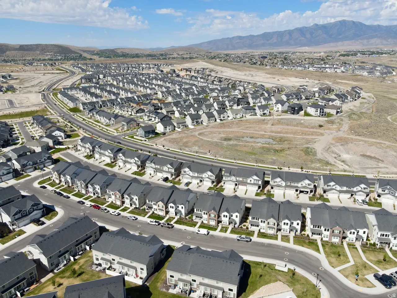 Expansive residential development featuring numerous single-family homes, paved streets, and a mountainous backdrop