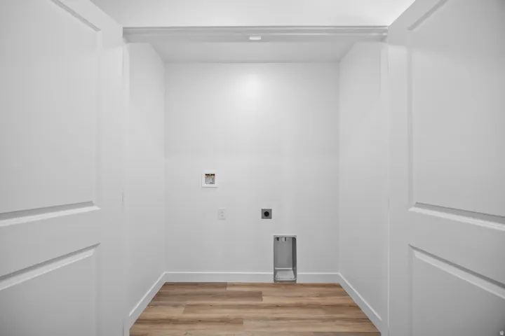 Dedicated laundry space featuring wood-finish flooring and bright white walls