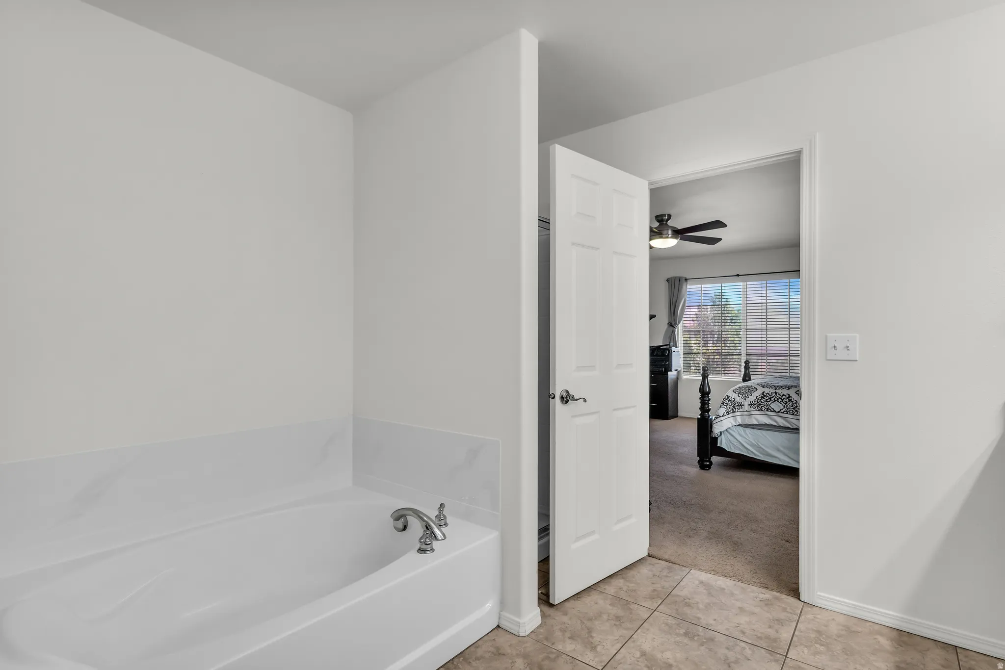 White soaking tub with chrome fixtures and a tile surround