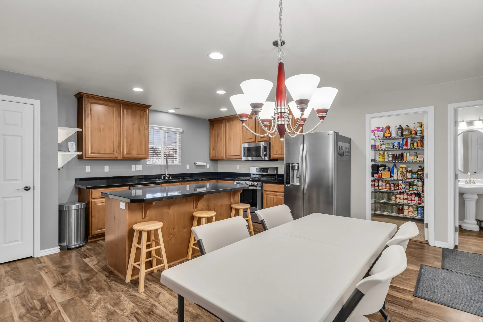 Open-concept kitchen and dining area featuring wood-finish flooring, recessed lighting, and a chandelier