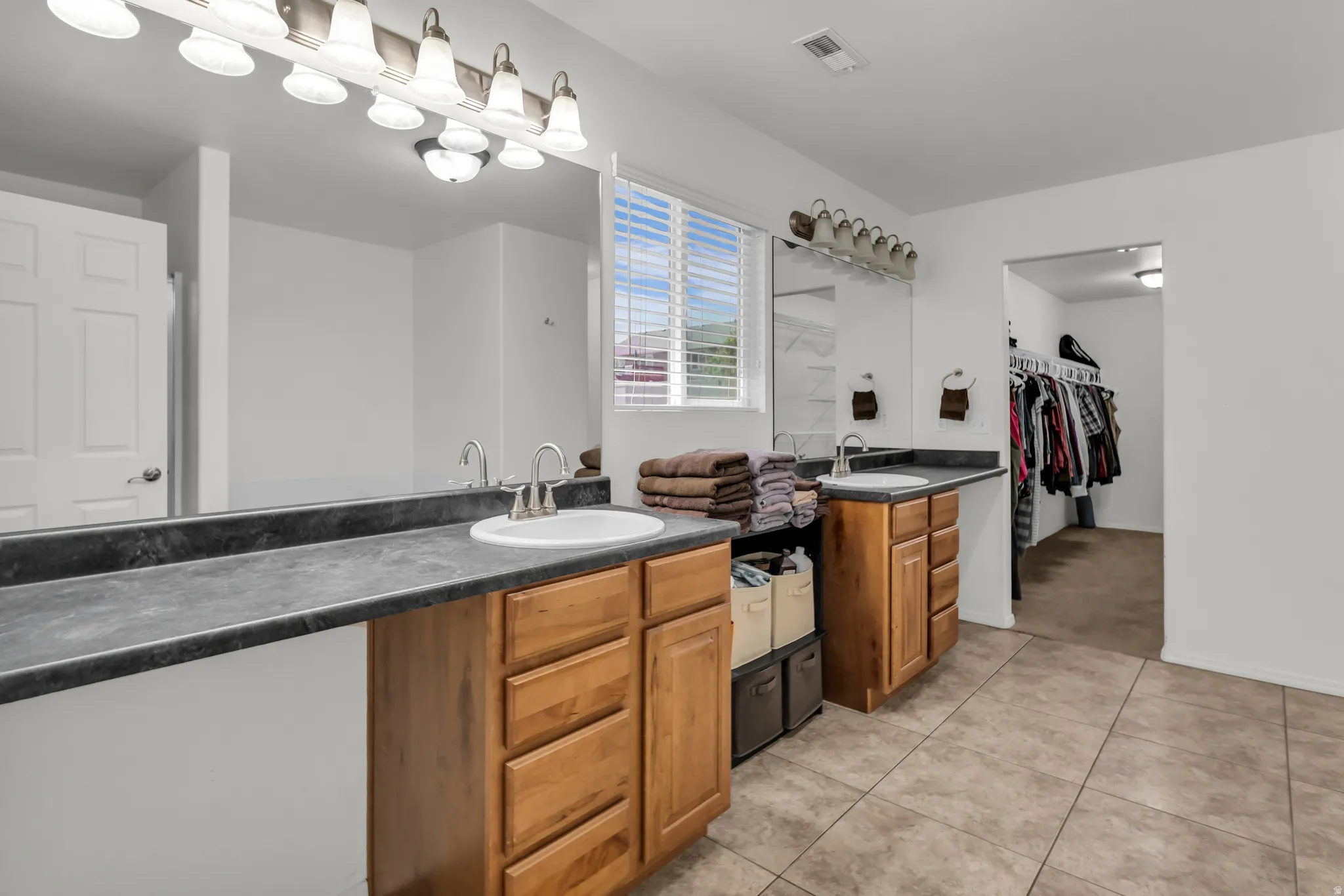 Double vanity with dark countertops, dual undermount sinks, and wood-finish cabinetry