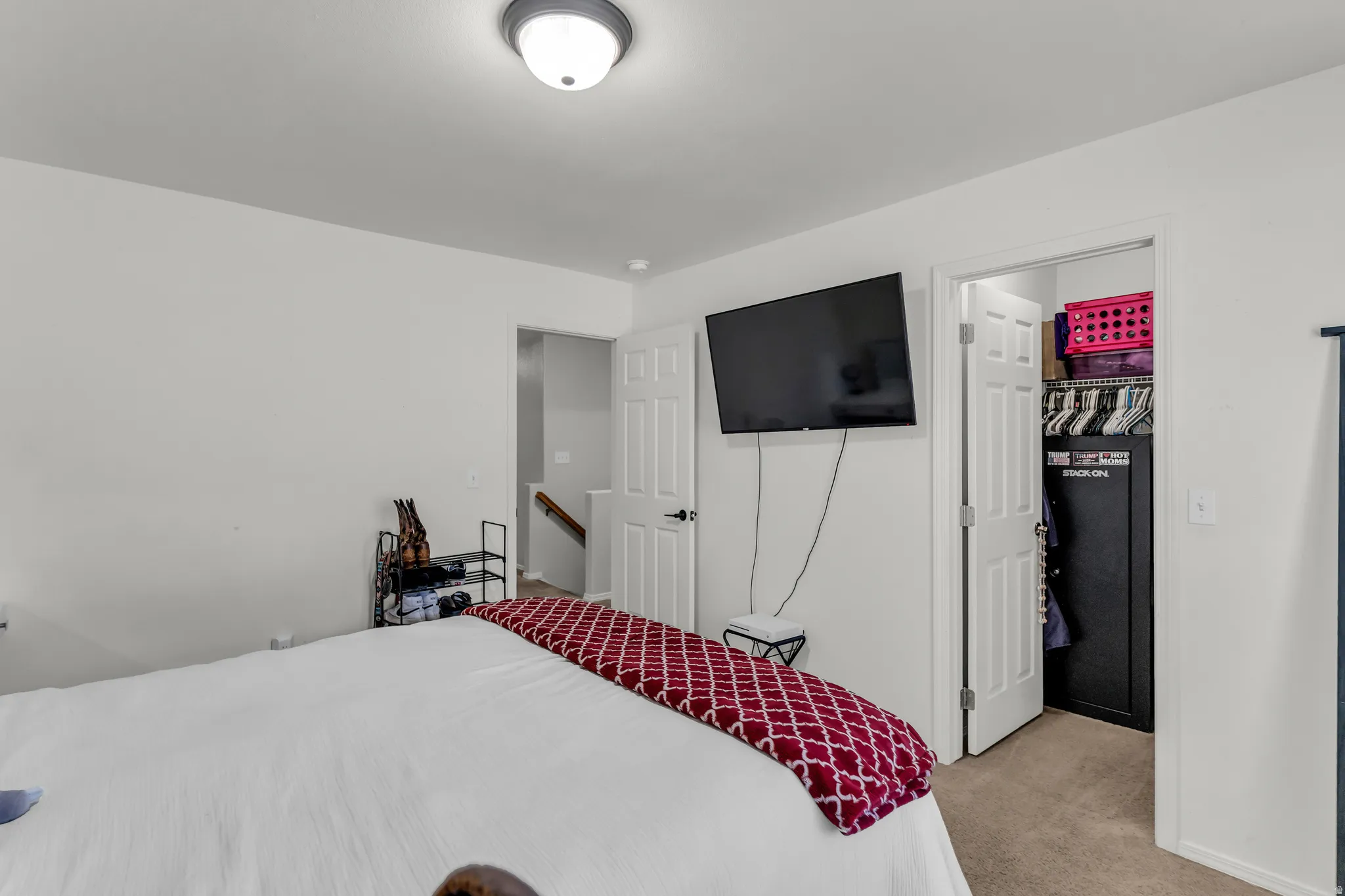 Bedroom featuring white walls, carpet flooring, a ceiling-mounted light fixture, and a built-in closet with a bi-fold door