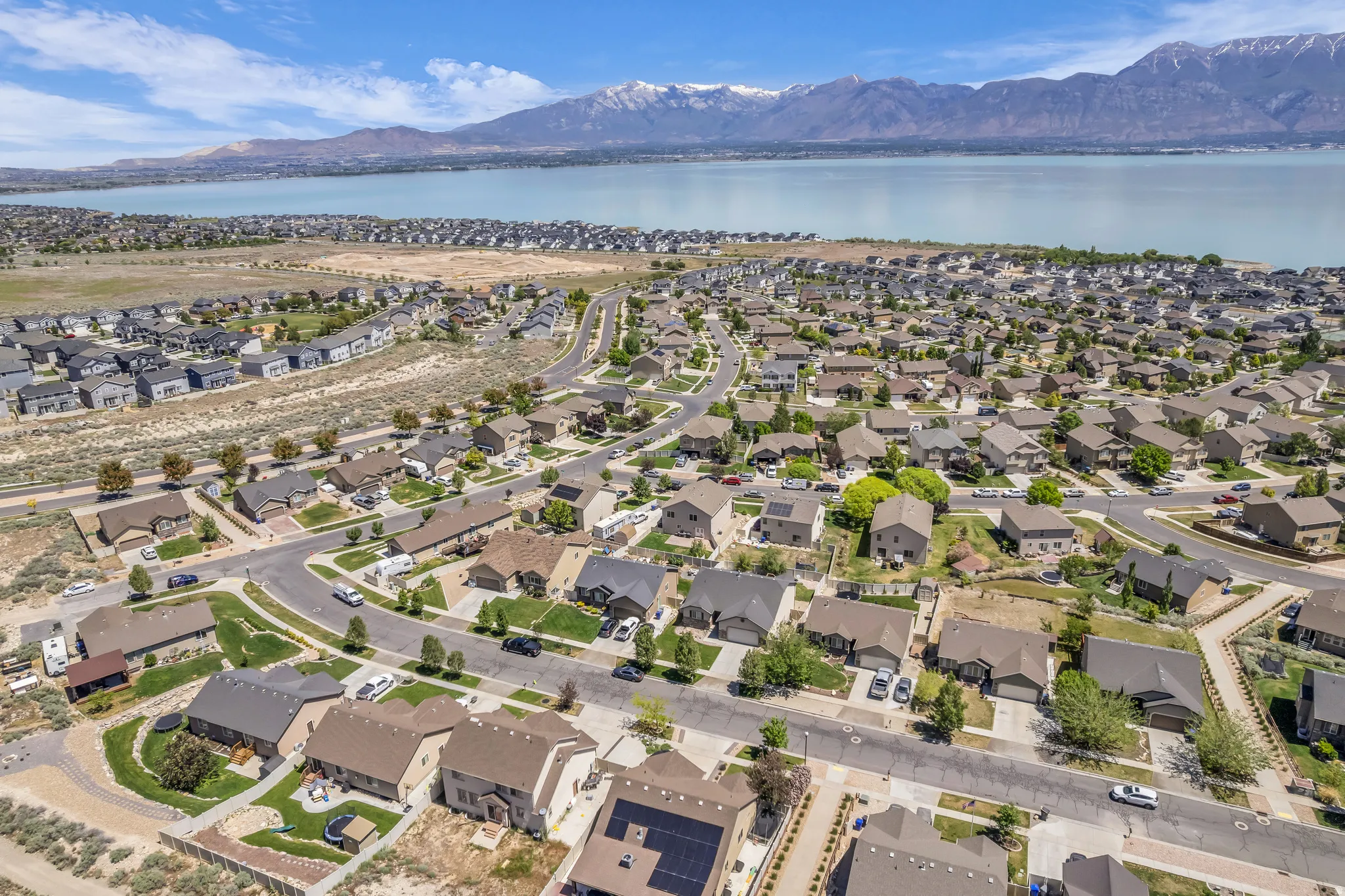 Aerial perspective showcasing a residential community with varied rooflines and a prominent body of water in the background