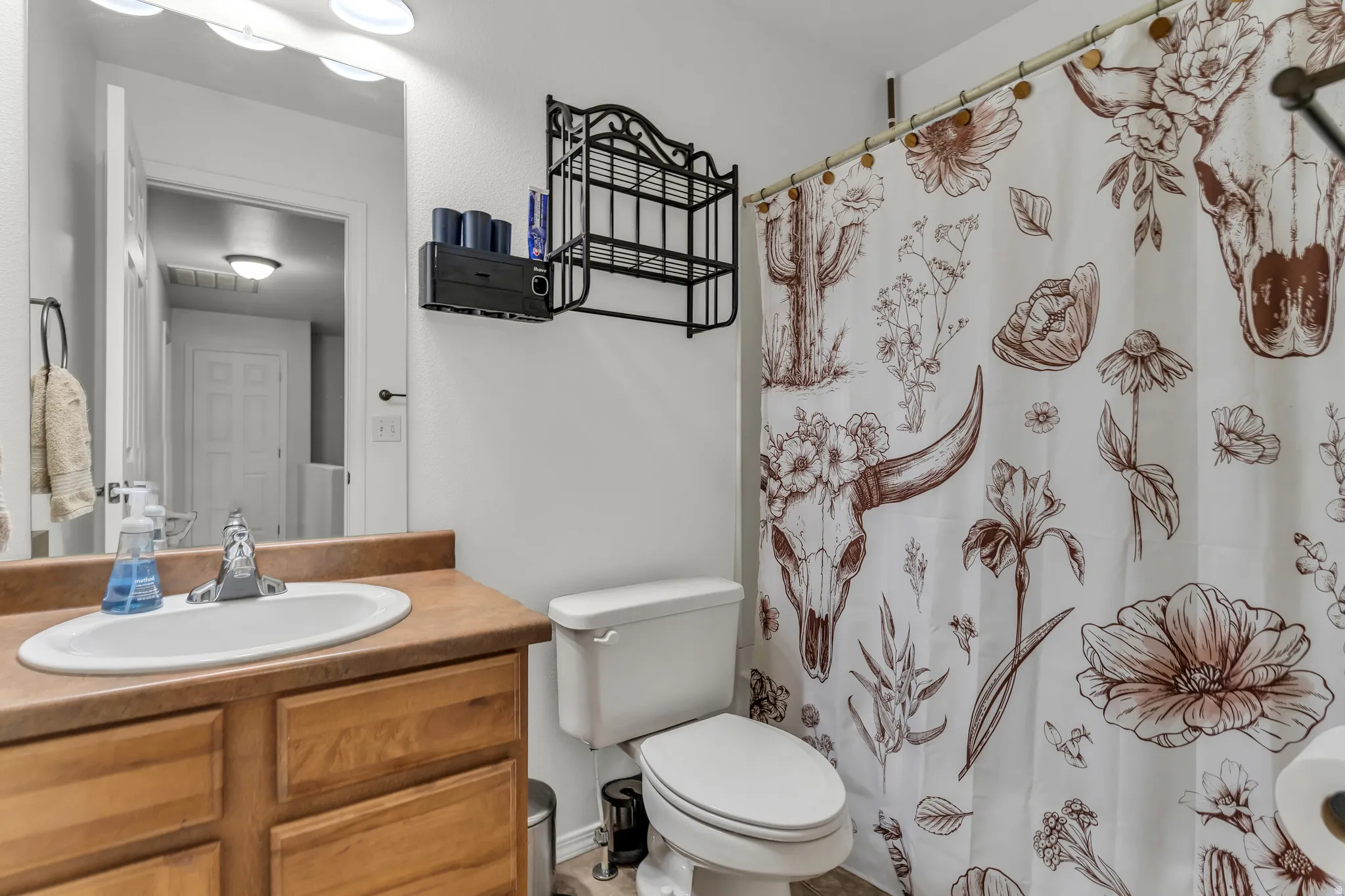 Bathroom featuring a vanity with wood-finish cabinetry, a built-in sink, and a counter-mounted faucet