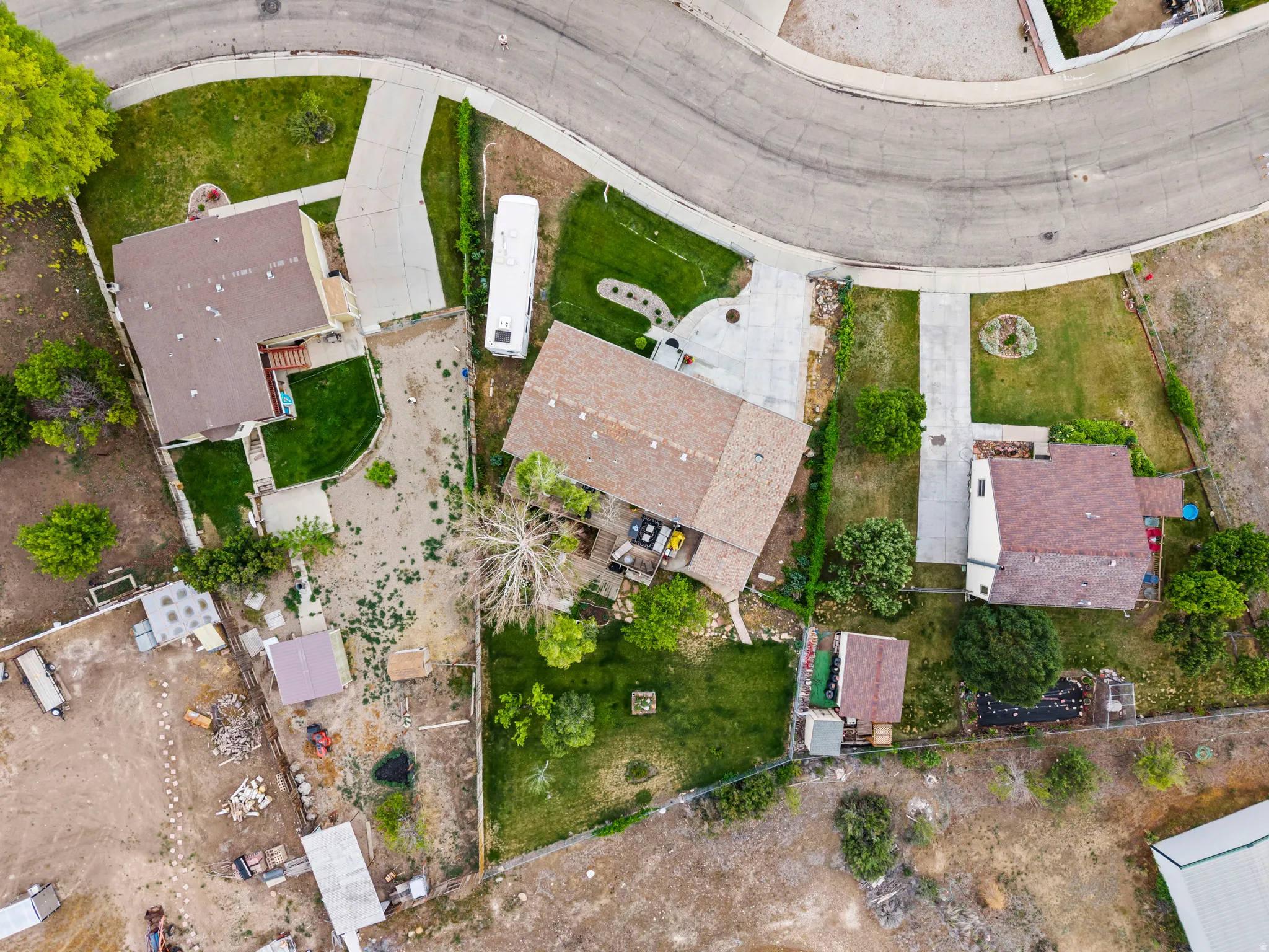 Aerial property overview showcasing a cul-de-sac location, a primary residence with a brown shingle roof, a concrete driveway, a manicured green lawn, and additional outbuildings