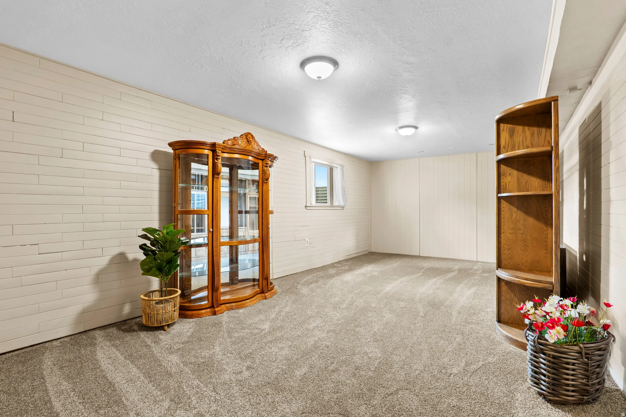 Spacious room featuring textured wall panels, recessed lighting, a window, and soft carpet flooring
