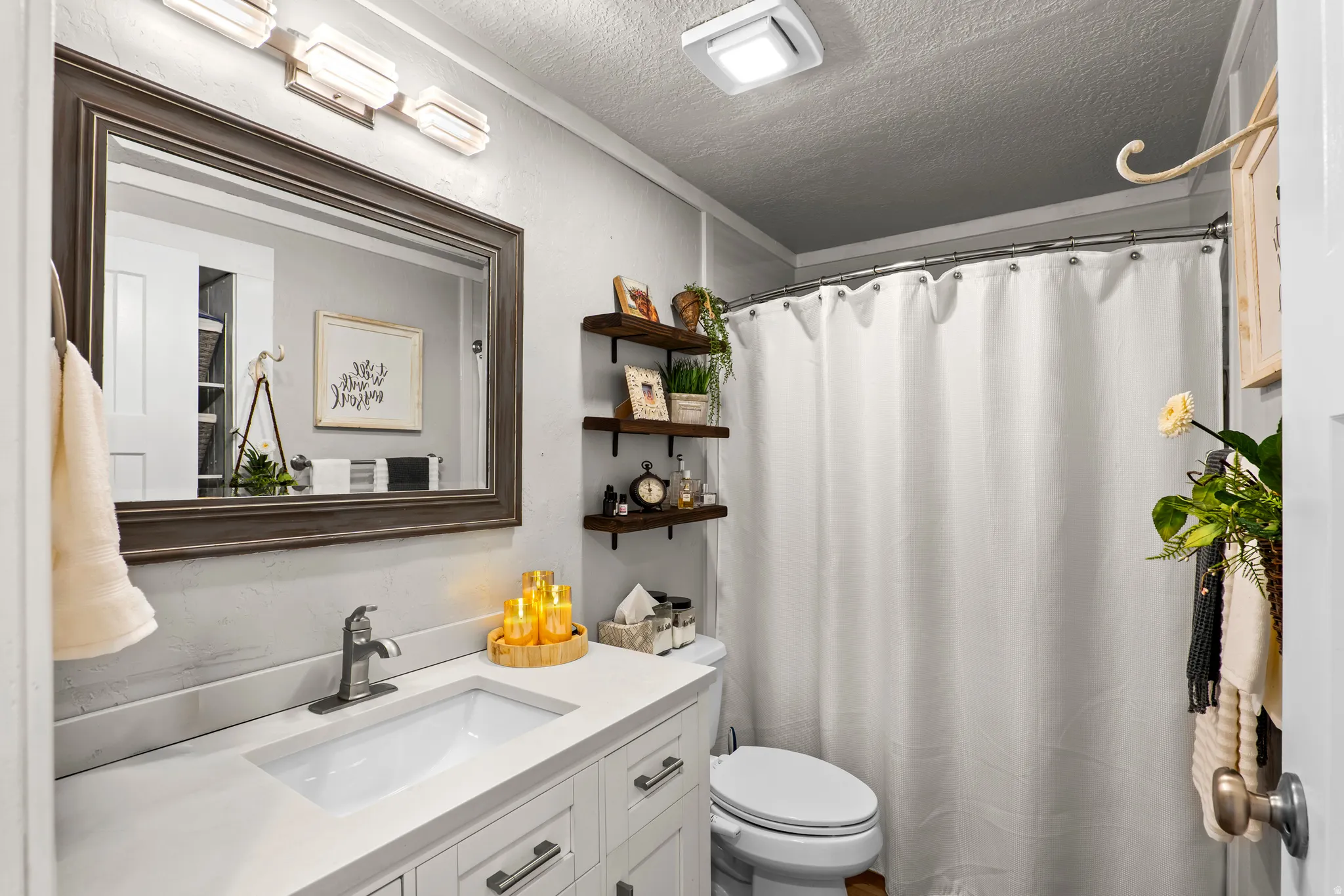 Bathroom featuring a white vanity with an integrated sink, brushed nickel faucet, and a framed mirror
