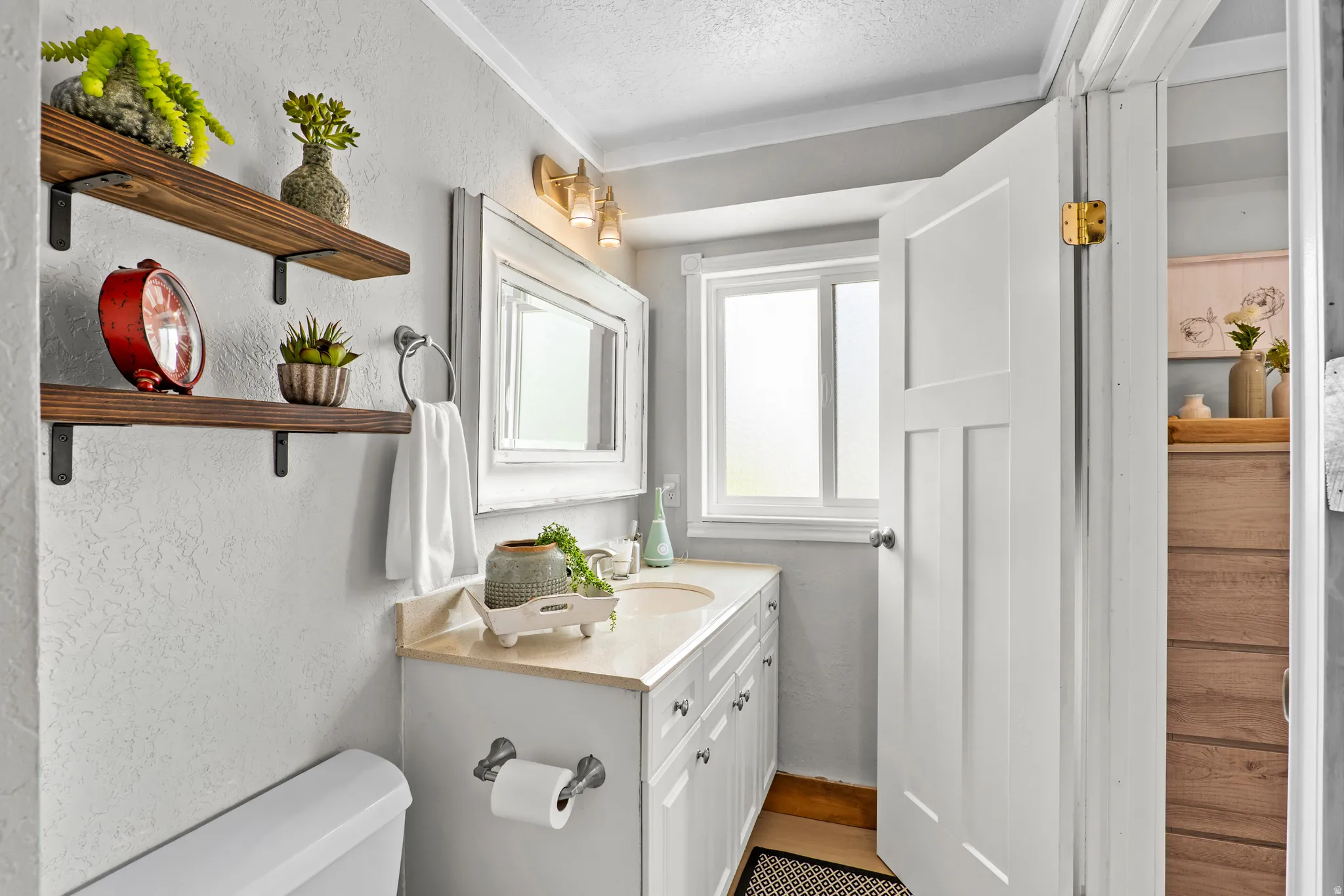 Bathroom featuring a vanity with an integrated sink and light-toned countertop, a rectangular mirror, and a three-light fixture