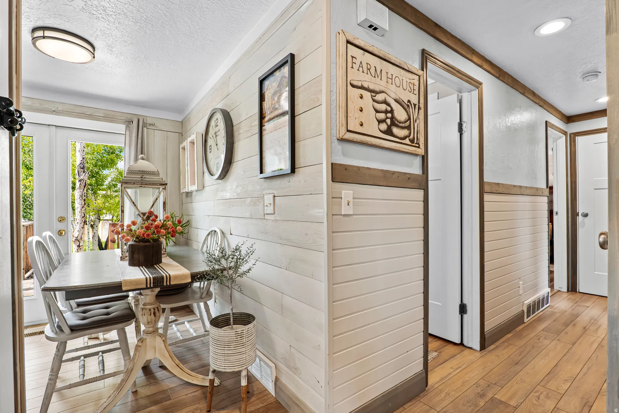 Dining area with shiplap wainscoting and wood-finish flooring