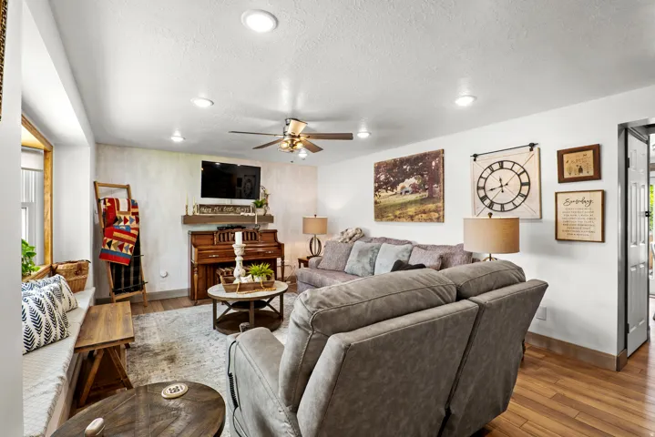 Bright living area featuring recessed lighting, a ceiling fan, wood-finish flooring, a built-in window bench, and a substantial wall-mounted television