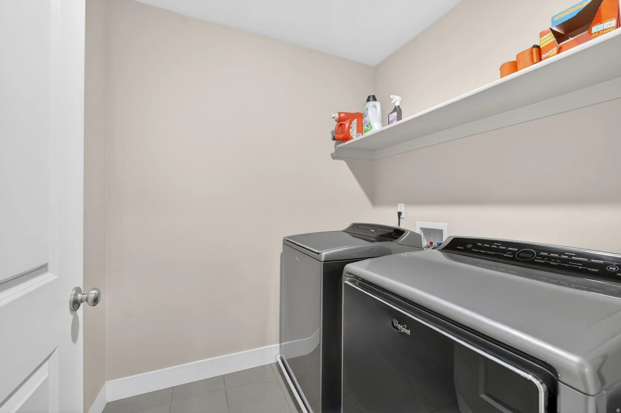 Utility space featuring light beige walls, a white baseboard, and a built-in white shelf