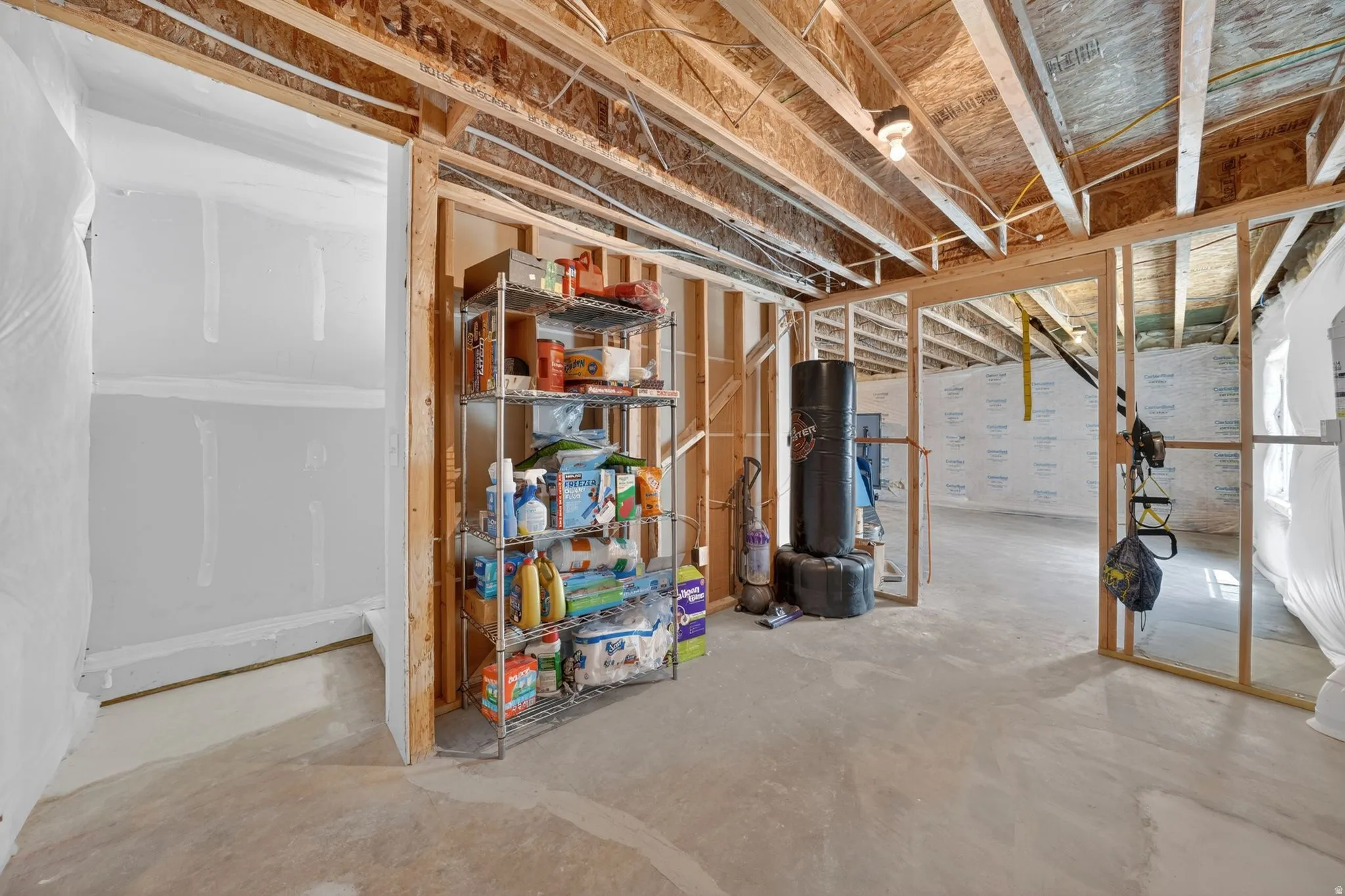 Unfinished basement space with exposed wooden framing and concrete flooring