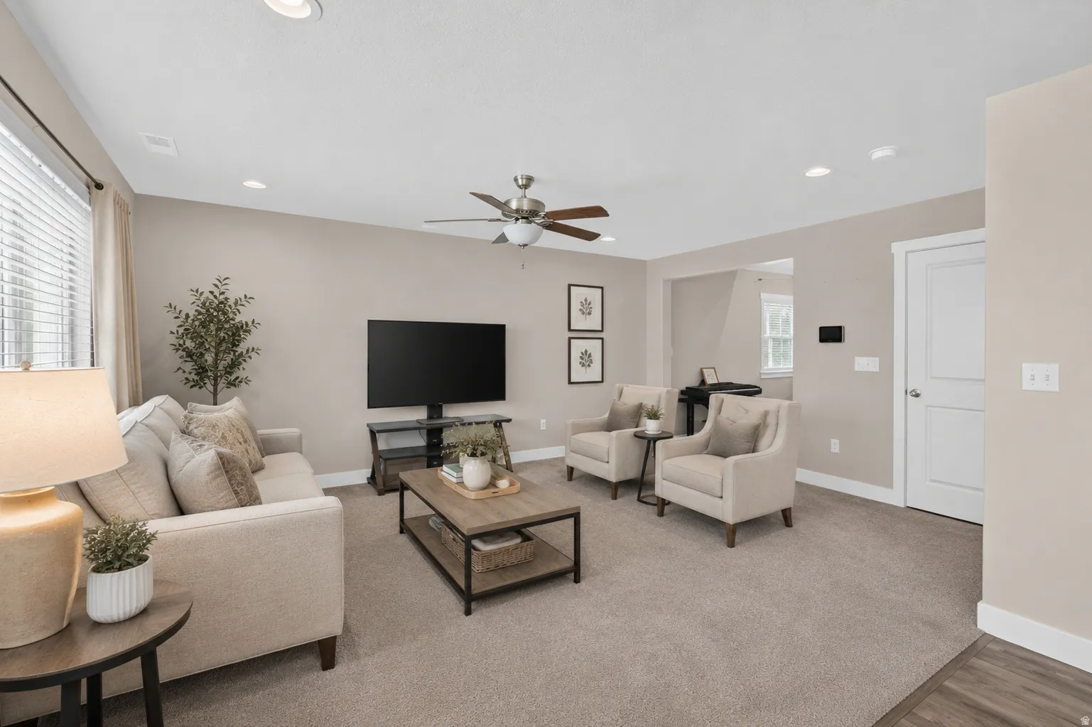 Carpeted living area featuring recessed lighting, a ceiling fan, a window with blinds, and neutral wall tones