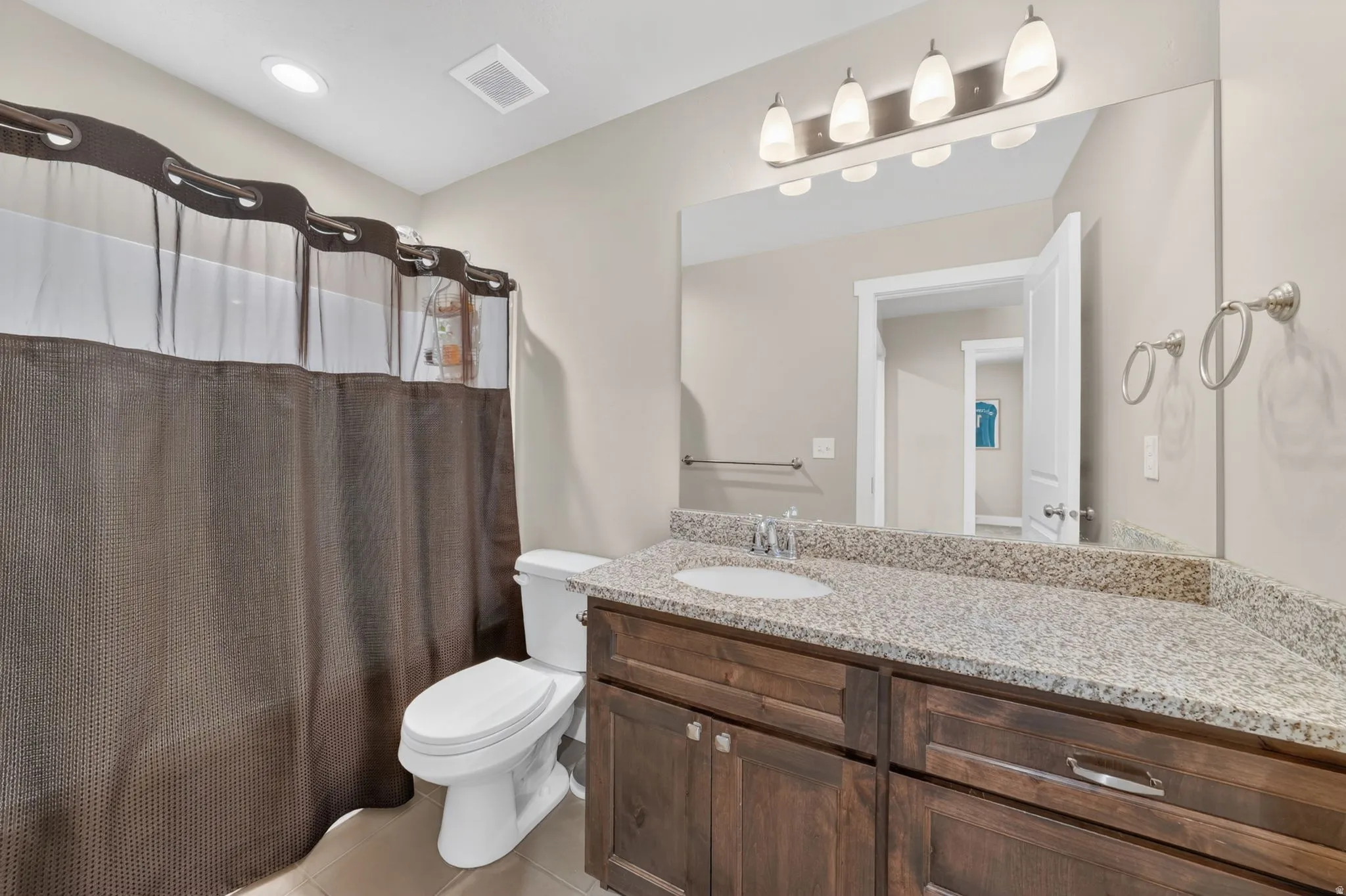 Bathroom vanity featuring a light-toned countertop with an integrated sink, dark wood-finish cabinetry, and brushed nickel hardware