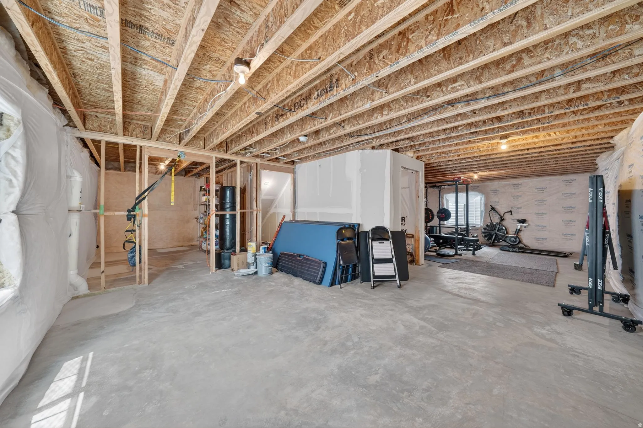 Unfinished basement presenting extensive open space, exposed wood joists, concrete flooring, and framed interior walls