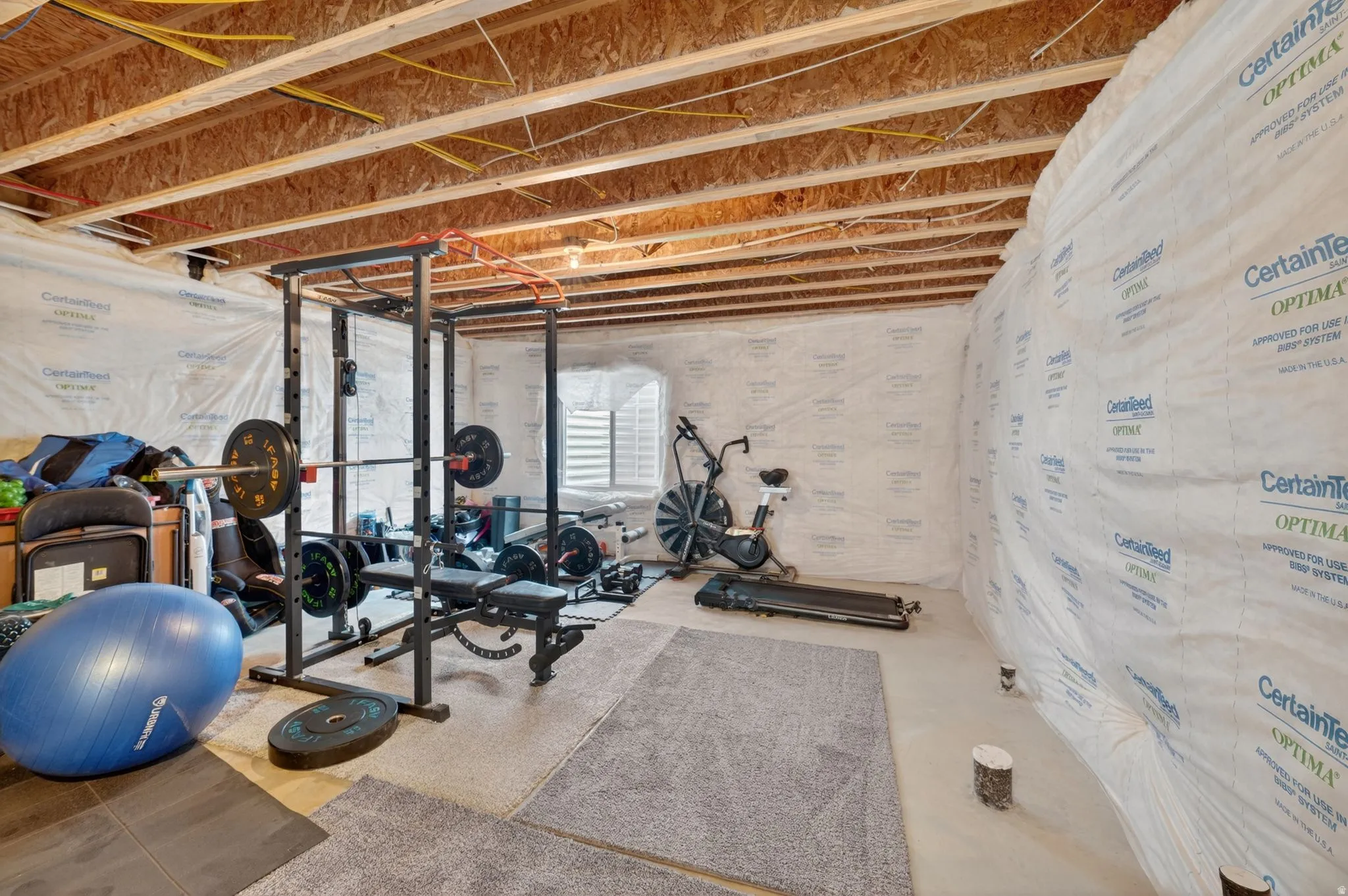 Unfinished basement area featuring exposed wood ceiling joists and wall insulation