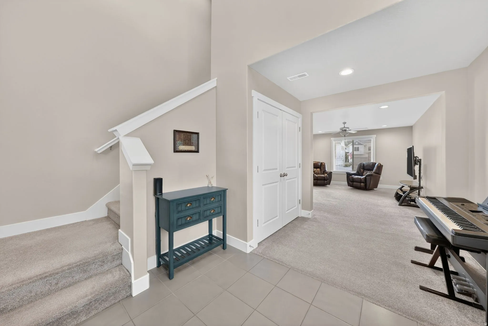 Entryway featuring tile flooring, leading to a carpeted staircase with a white railing