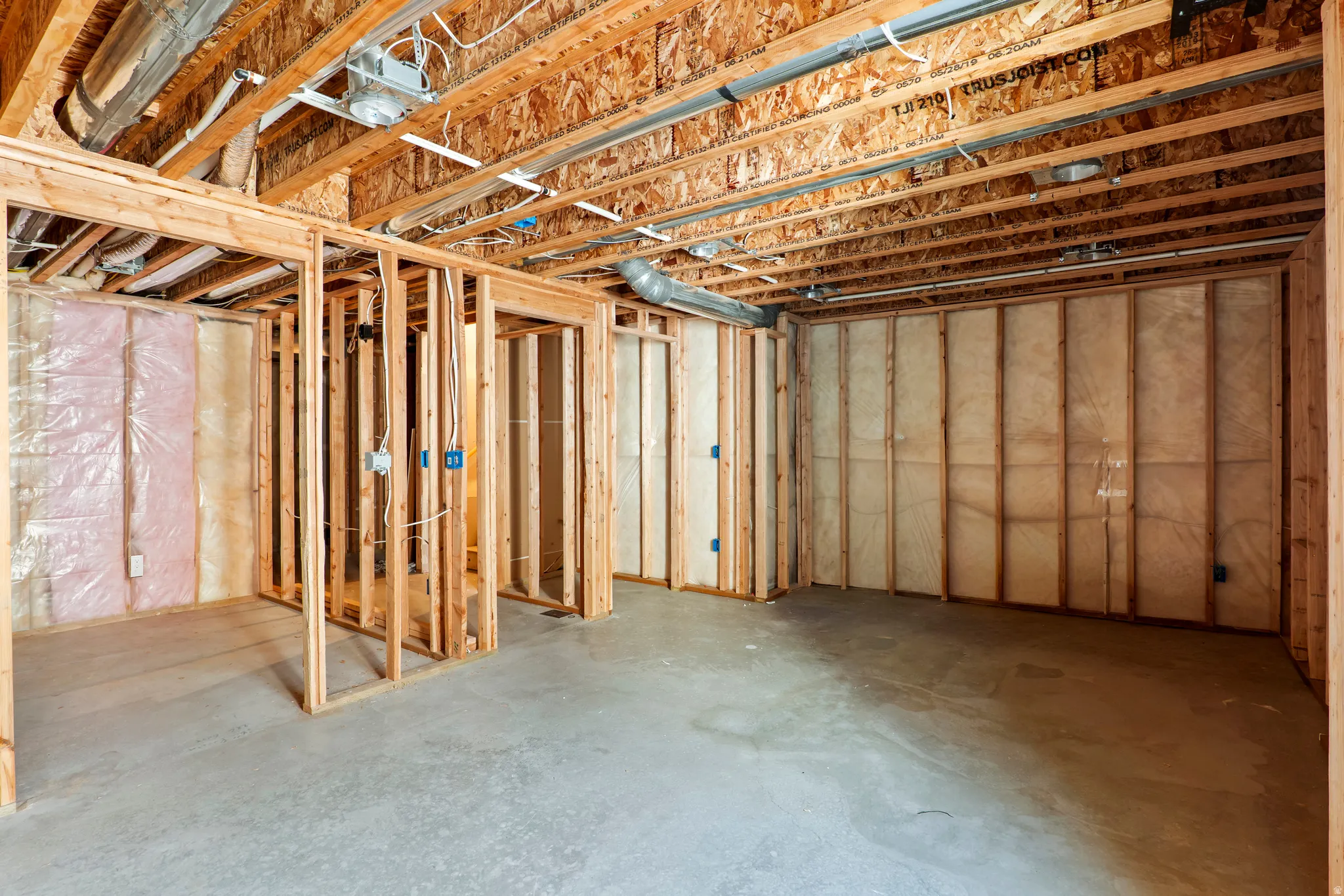 Unfinished basement offering exposed wood framing, concrete flooring, and visible insulation