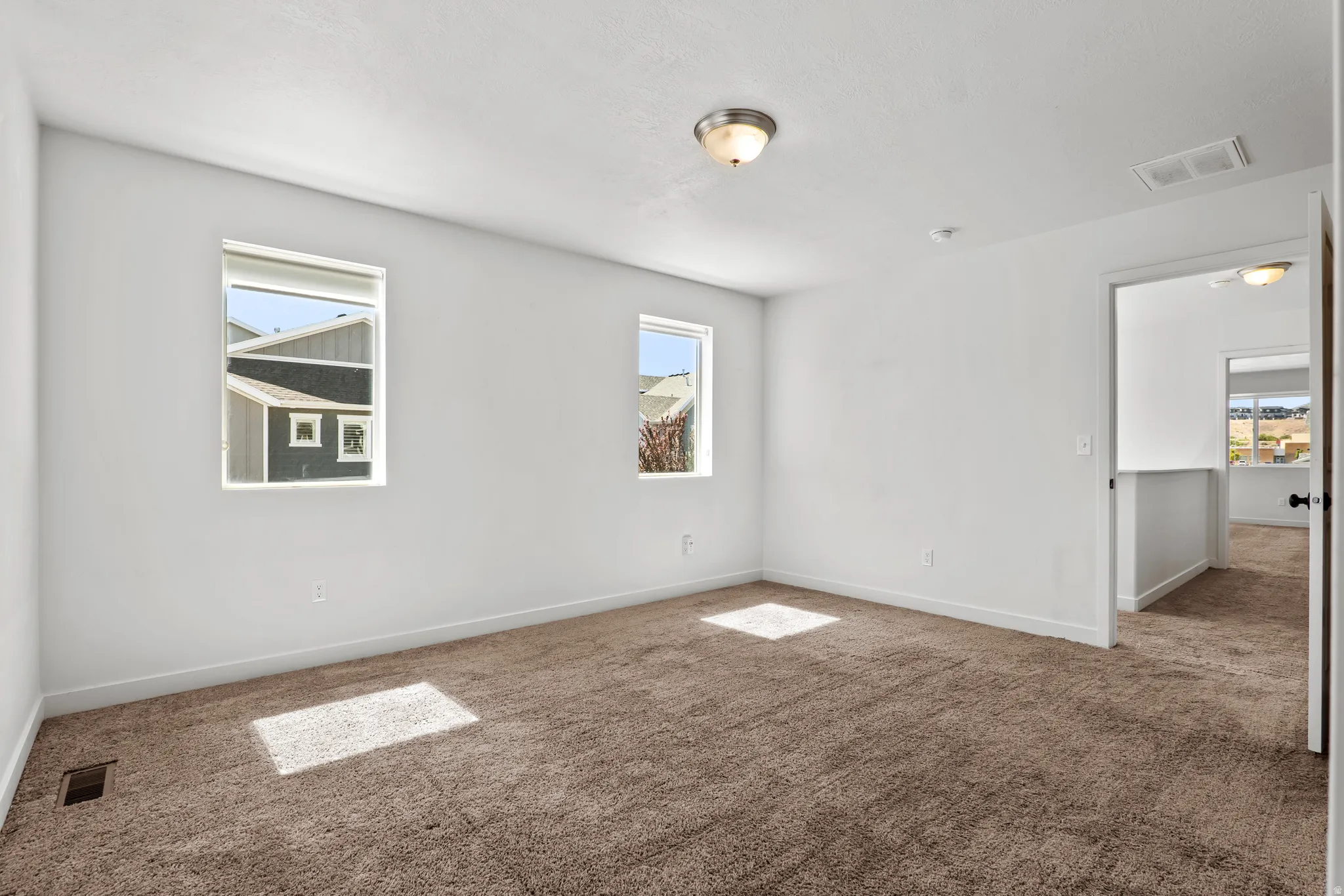 Carpeted room featuring white walls, two windows with white trim, and a semi-flush mount ceiling light