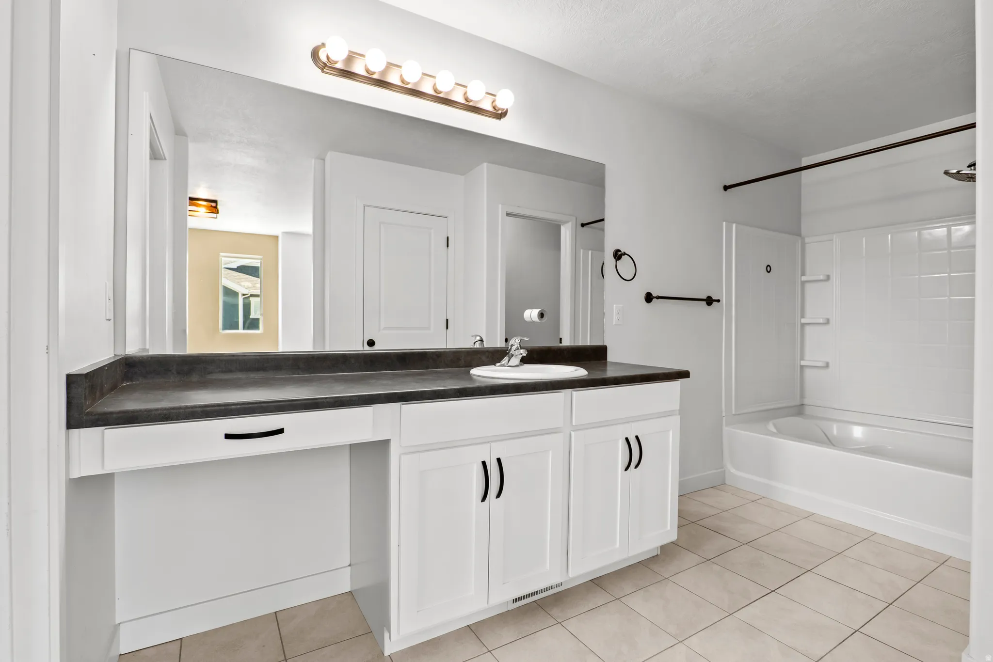 Bathroom featuring a single vanity with a dark countertop, white cabinetry, and a full-width mirror