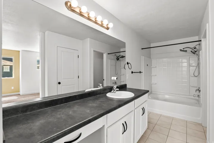 Contemporary bathroom featuring a large vanity with white cabinetry, dark countertop, and an integrated sink