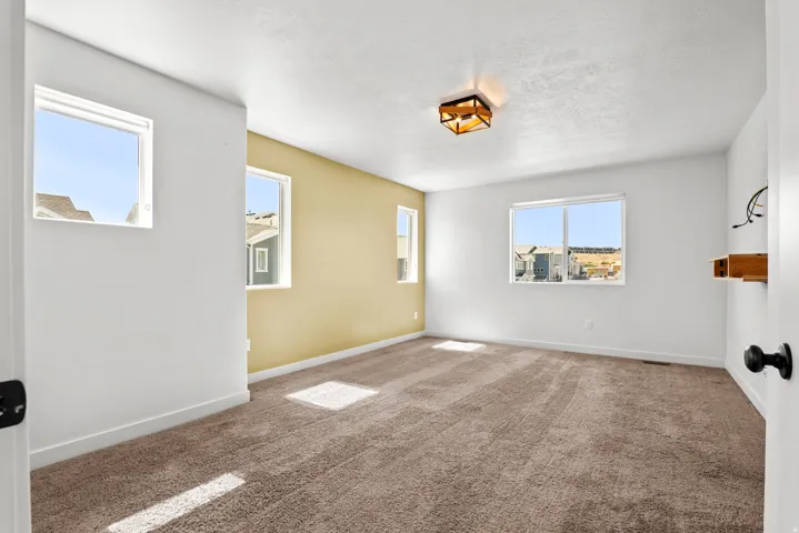 Spacious room with plush brown carpeting and white walls, accented by a yellow feature wall