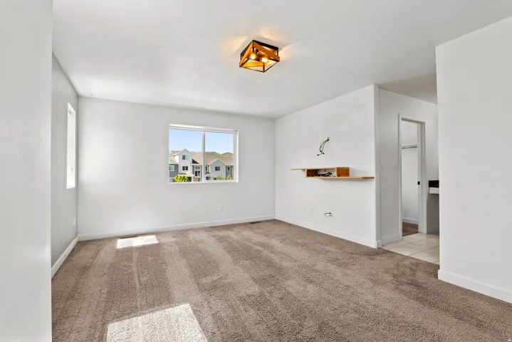 Spacious interior room with neutral-toned carpeting and white walls