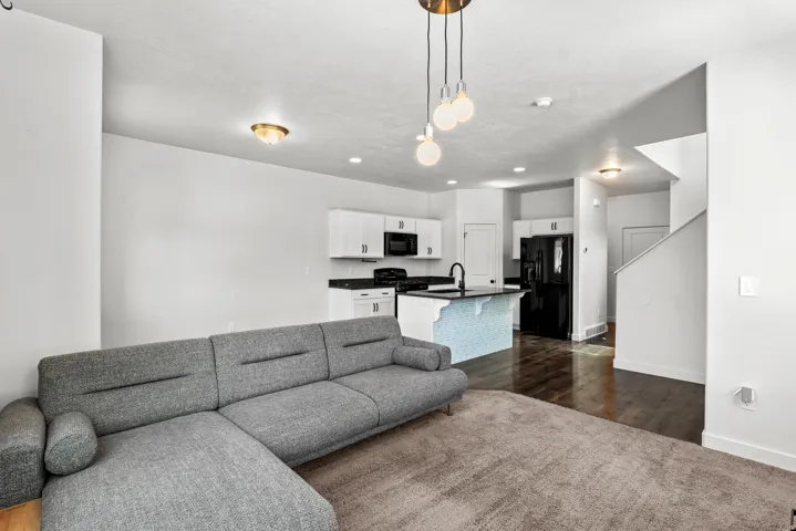 Open-concept living space featuring wood-finish flooring, recessed lighting, and a contemporary pendant fixture