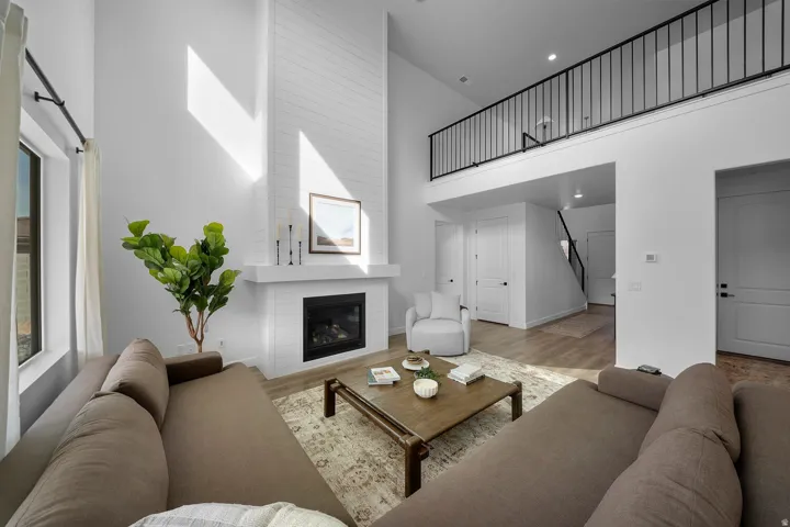 Great room featuring a shiplap-accented fireplace with a white mantel, high ceilings, and wood-finish flooring