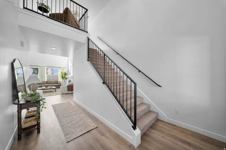 Split-level entry featuring a modern black railing system, carpeted stairs, and wood-finish flooring