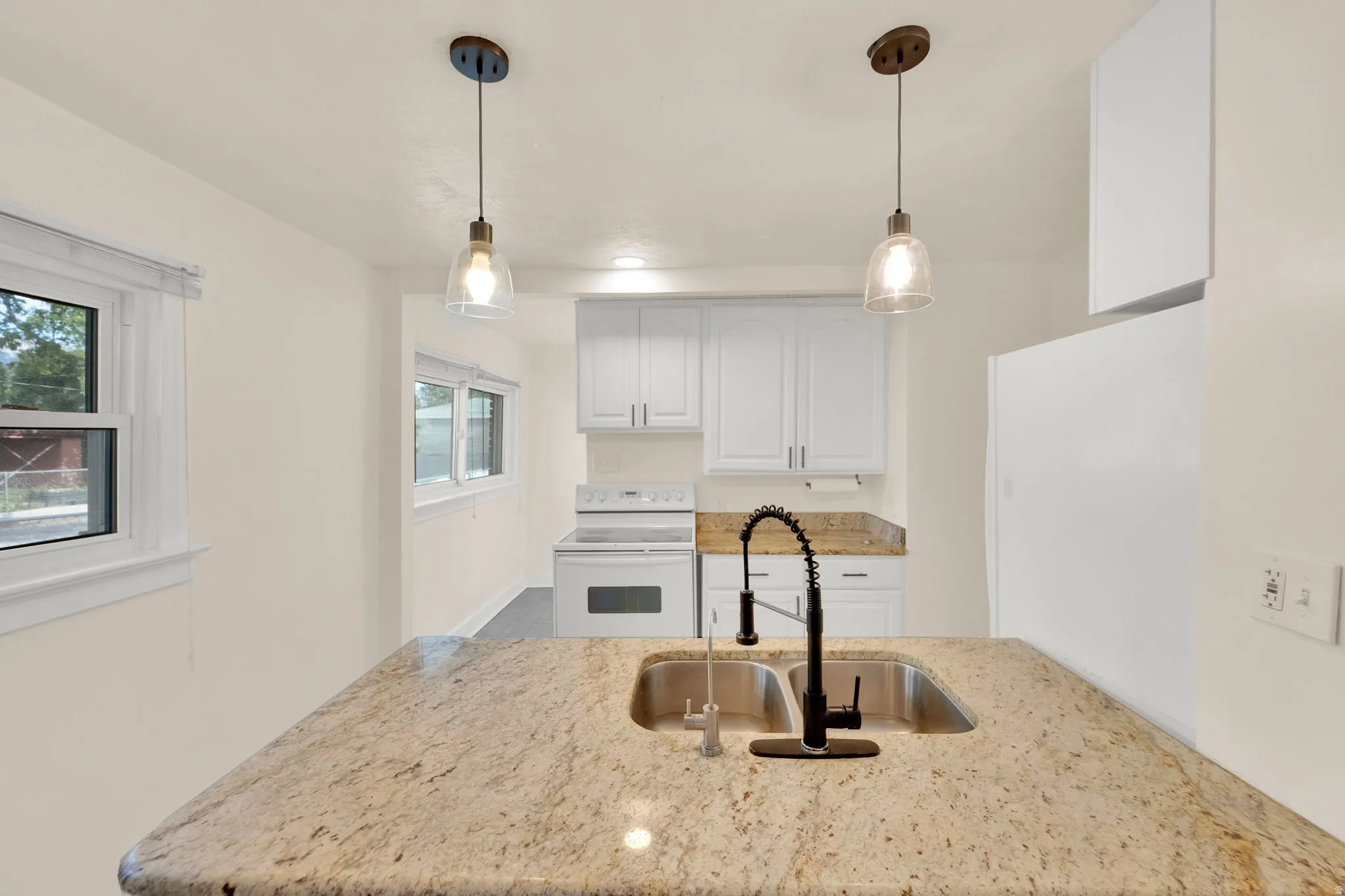 Kitchen featuring a peninsula with a dual-basin stainless steel sink, a matte black pull-down faucet, and granite countertops