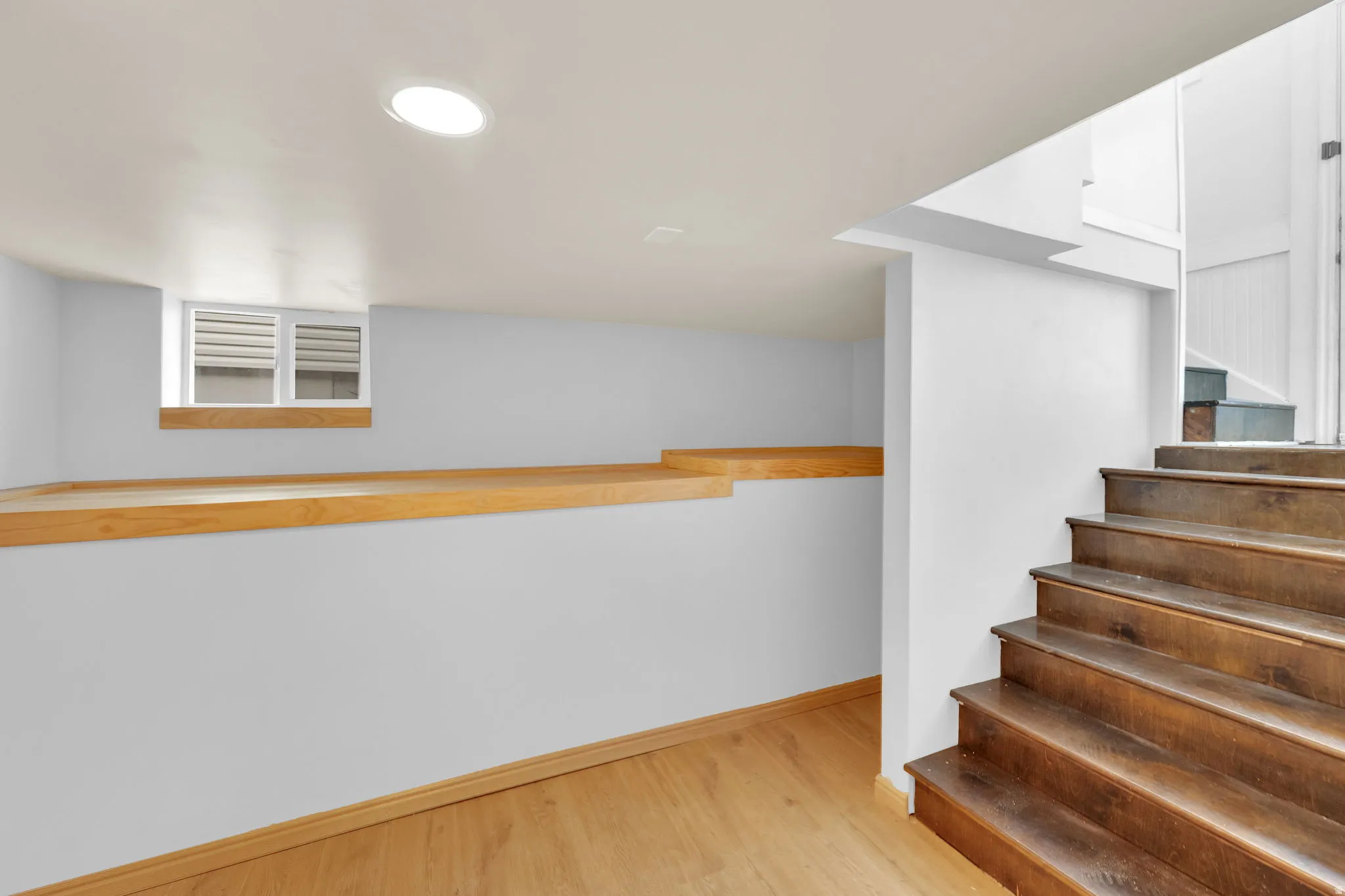 Lower level space featuring wood-finish flooring, recessed lighting, and a window with blinds