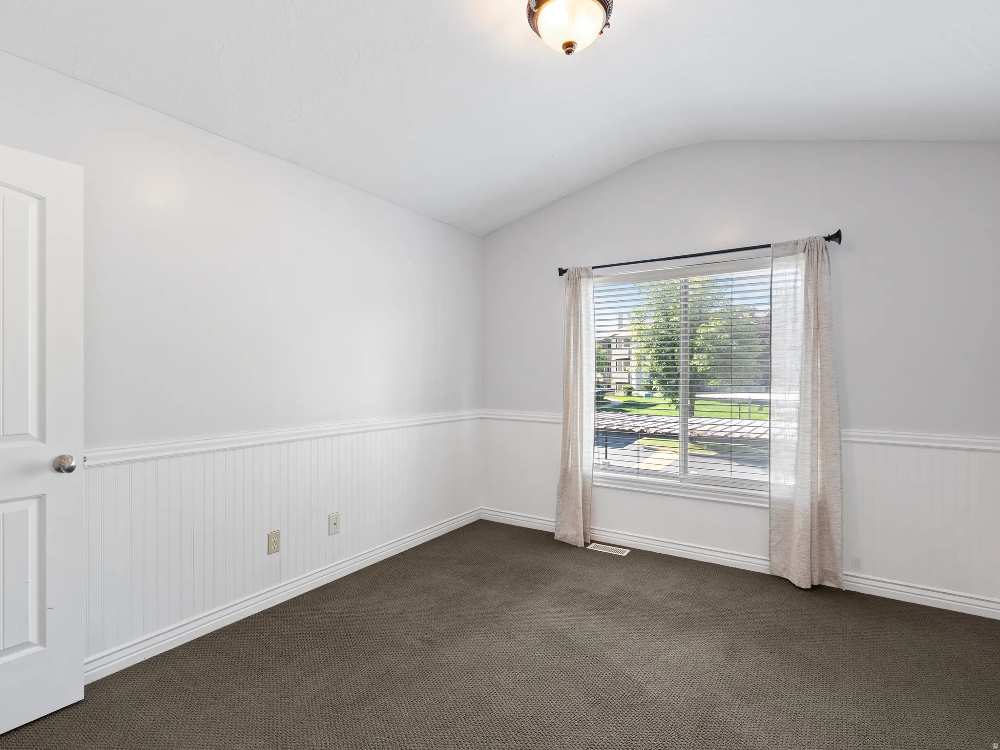 Interior room with wainscoting and a vaulted ceiling