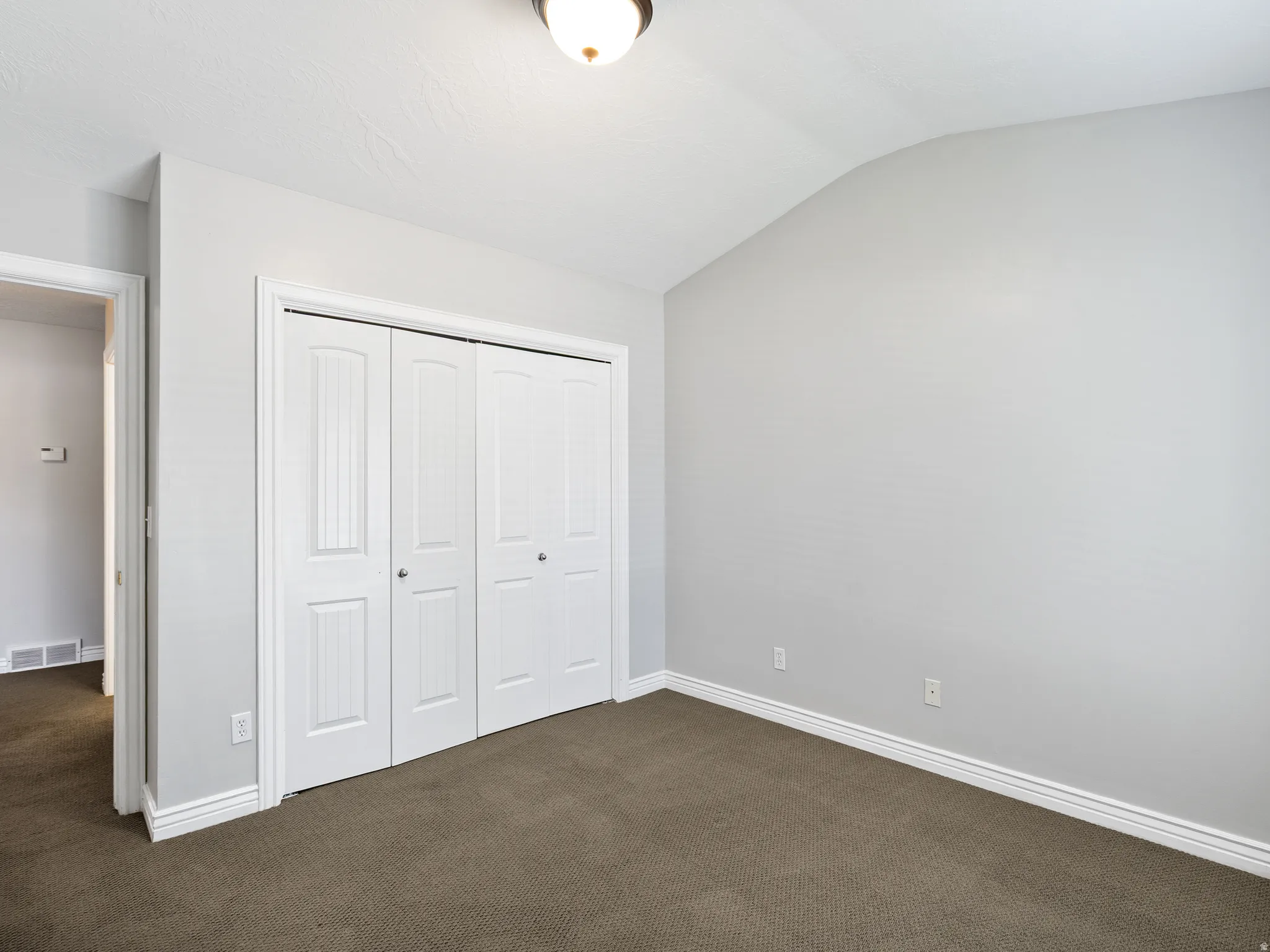 Interior room featuring neutral gray walls, brown carpet flooring, and white baseboards