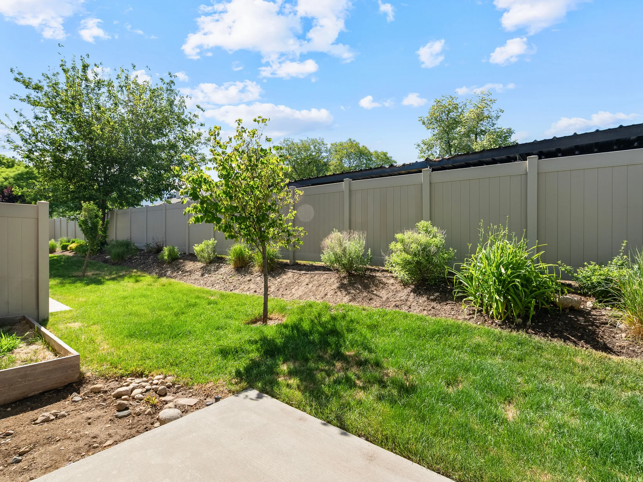 Expansive outdoor space featuring a concrete patio and a raised garden bed