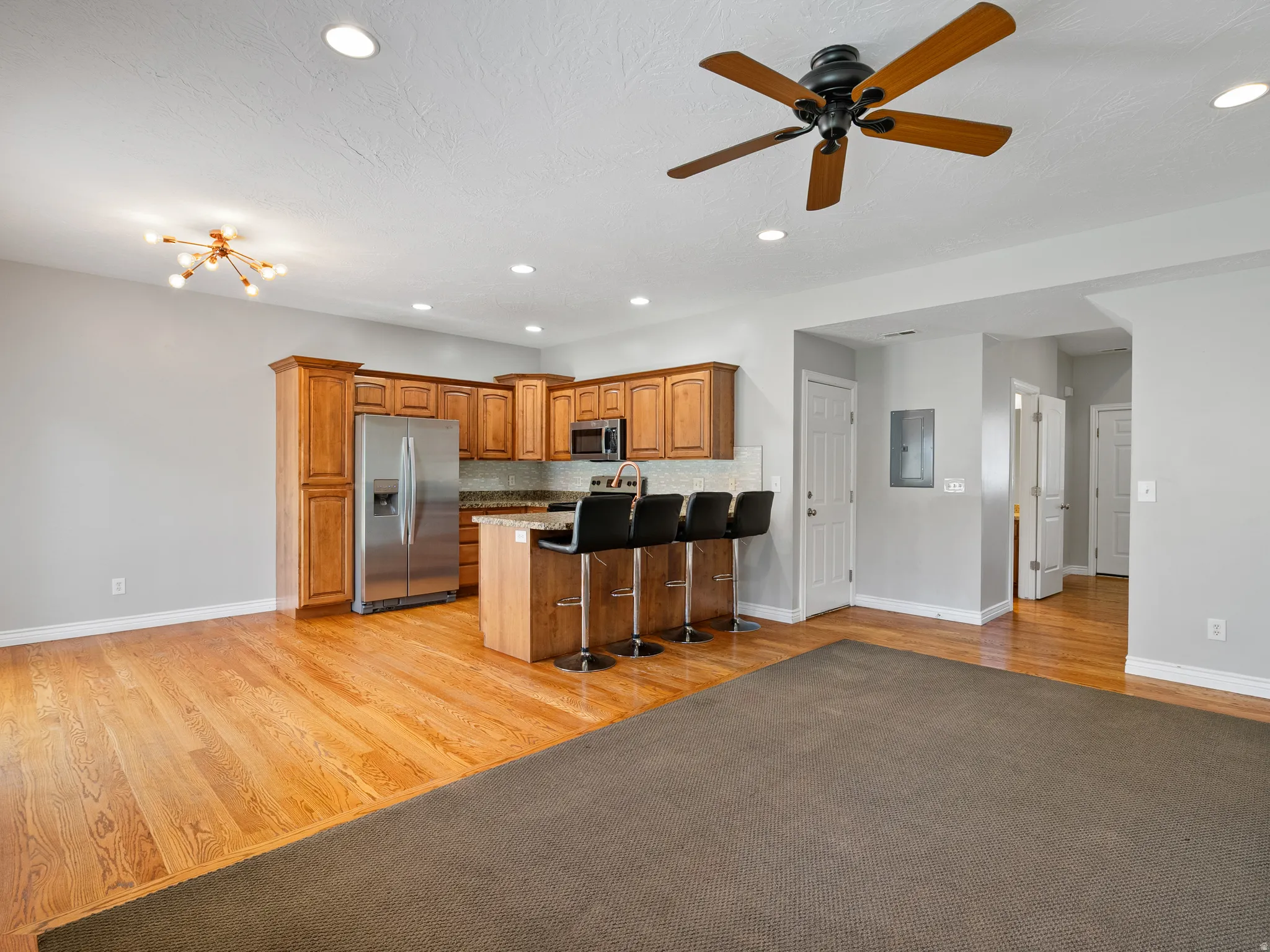 Open-concept interior featuring a kitchen with wood cabinetry, stainless steel appliances, and a breakfast bar