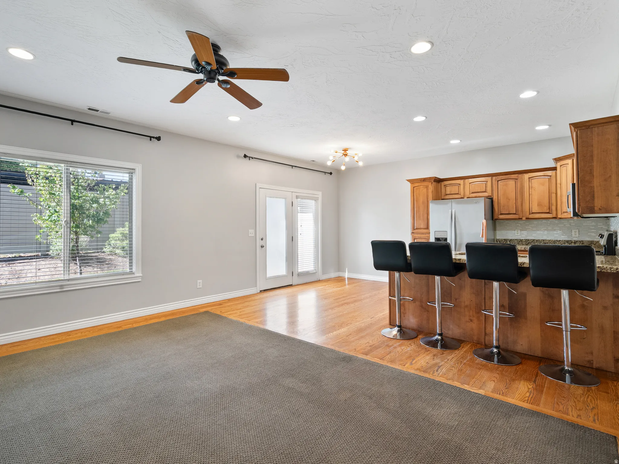 Open concept living space featuring a kitchen island with seating, wood-finish flooring, and recessed lighting