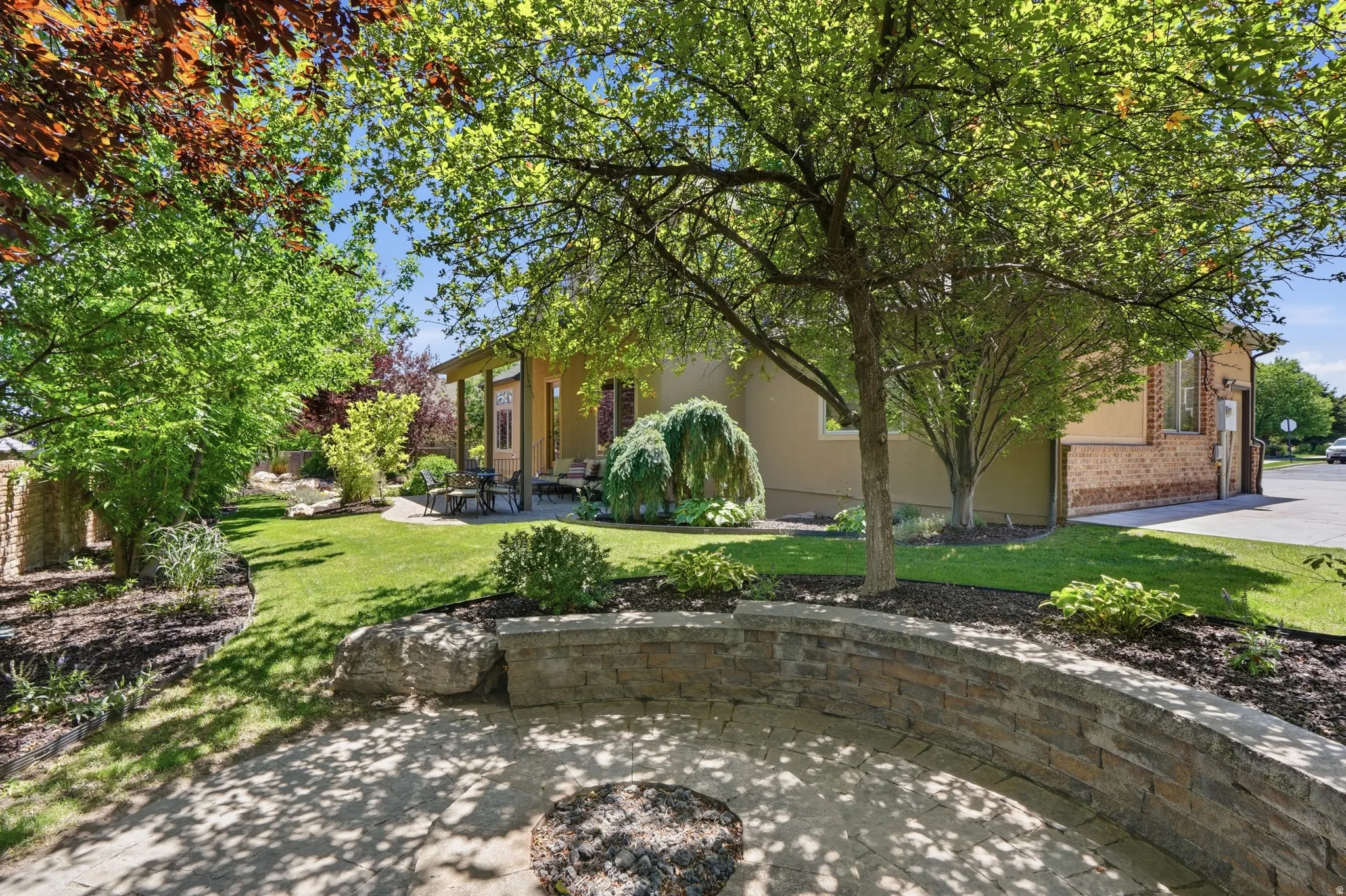 Spacious outdoor living area with a paver patio and a stone seating.