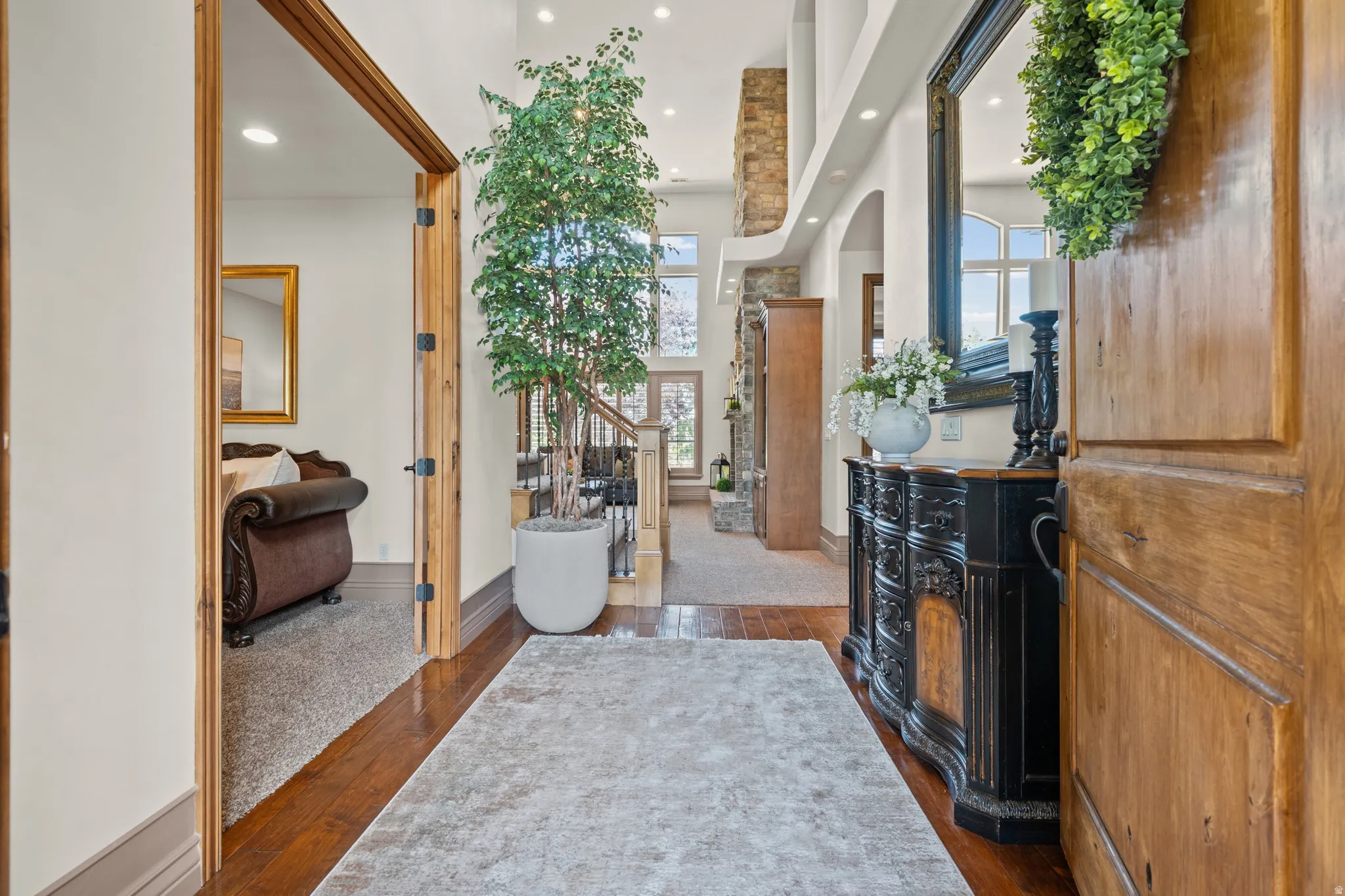 Hardwood flooring extending from the entryway into the main living areas, featuring a grand staircase with wrought iron balusters