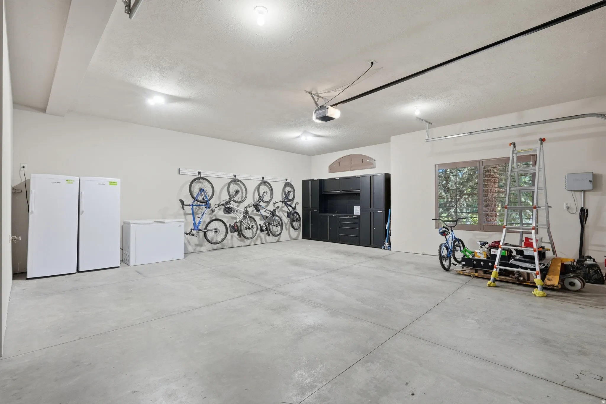 Spacious garage with concrete flooring, recessed lighting, built-in storage cabinetry, and a large window