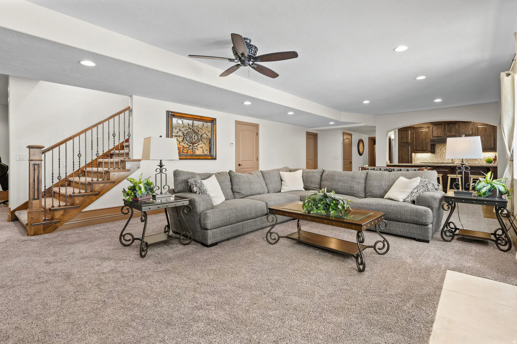 Spacious living area featuring neutral carpet flooring, recessed lighting, and a ceiling fan