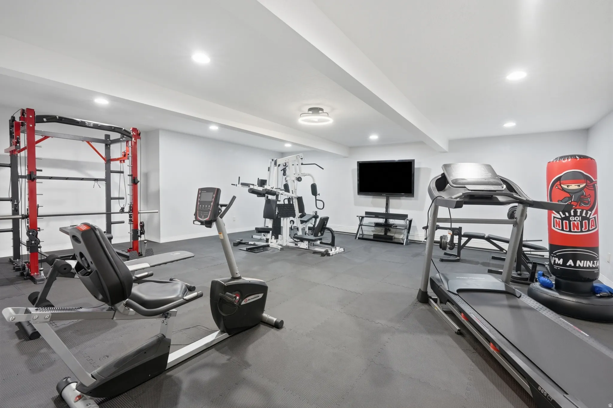 Dedicated fitness space featuring rubber flooring, recessed lighting, and a ceiling-mounted fixture