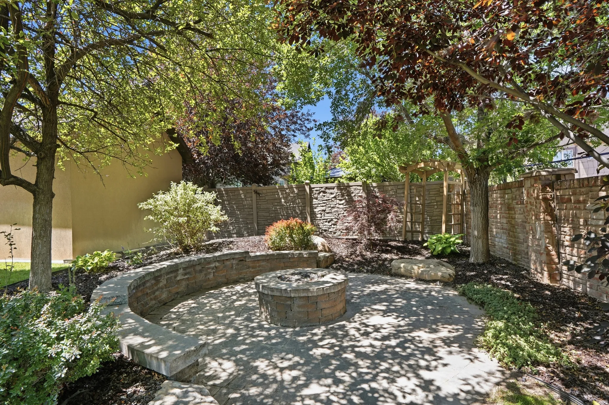 Stone paver patio featuring a circular stone fire pit and seating, beautiful canopy of trees.