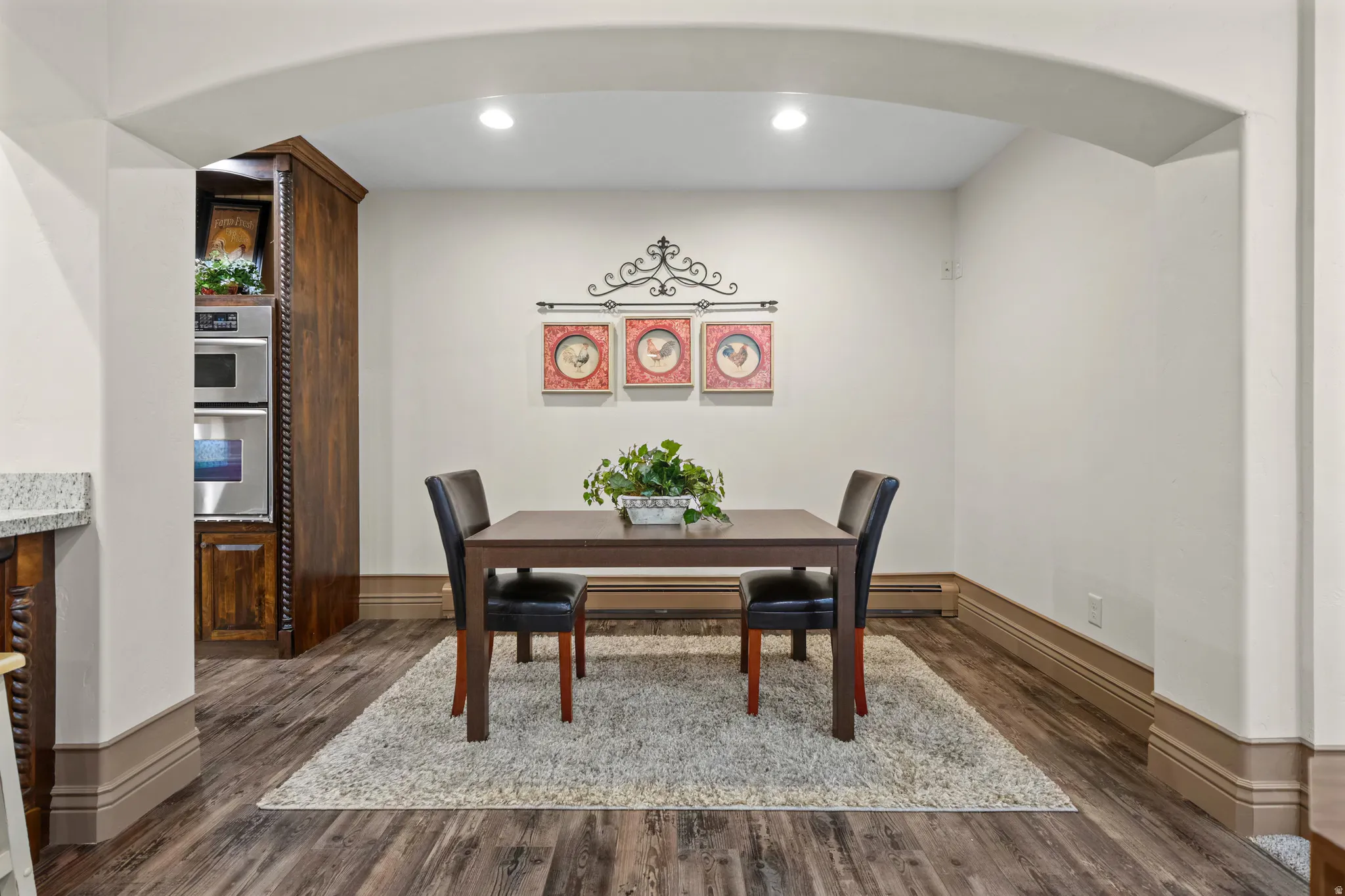 Arched entryway leading into a space with wood-finish flooring, recessed lighting, and substantial baseboard and trim molding