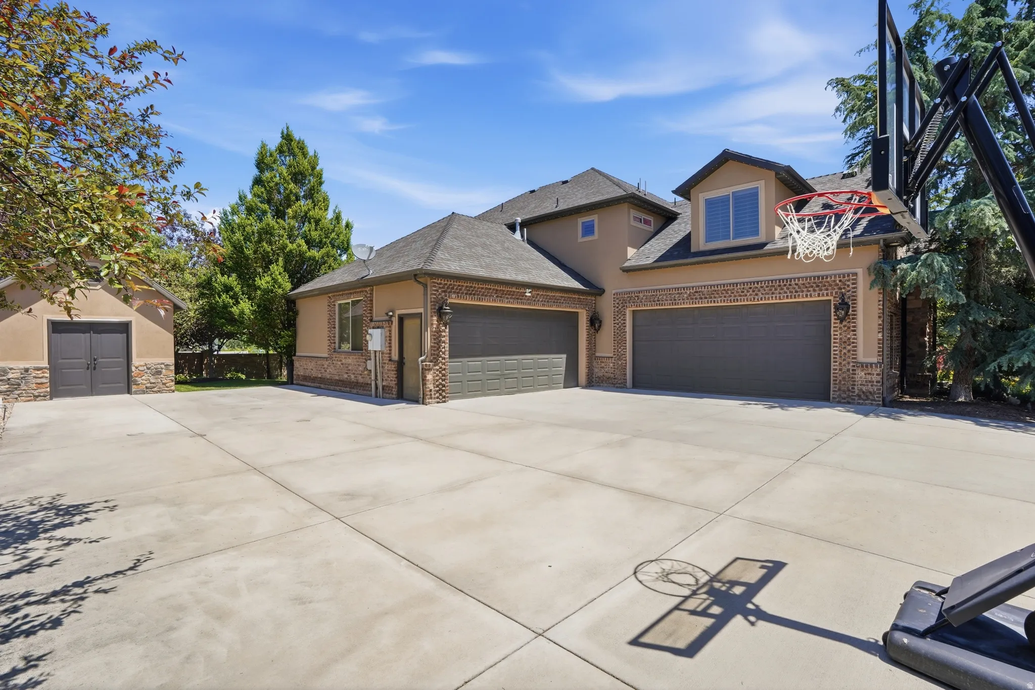 Expansive concrete driveway featuring a two-car attached garage and a detached single-car garage