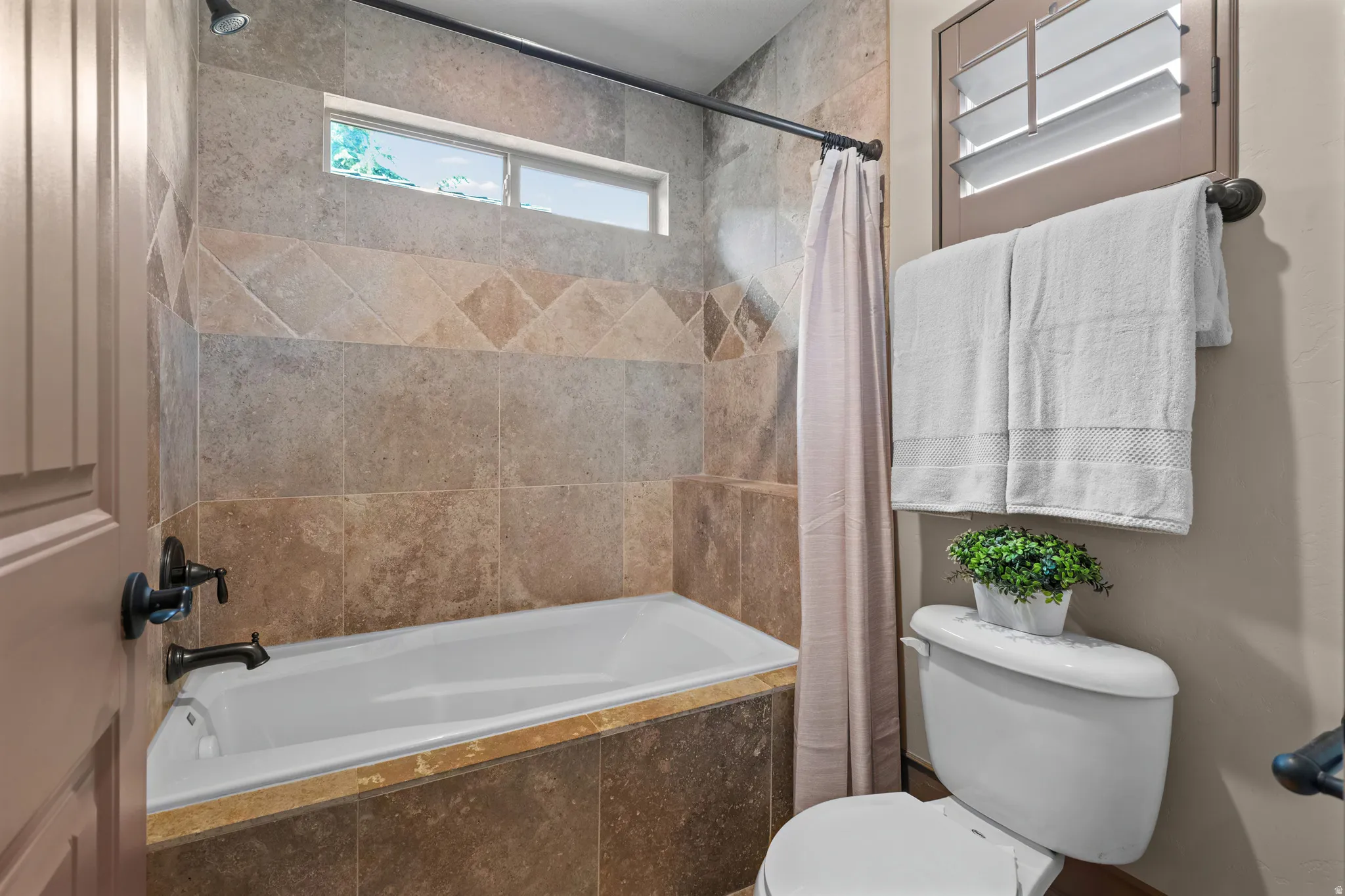 Bathtub with stone-look tile surround and oil-rubbed bronze fixtures