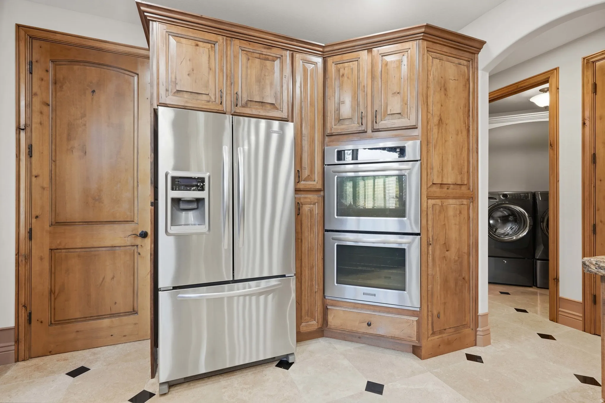 Stainless steel French door refrigerator and double wall ovens integrated into custom wood cabinetry