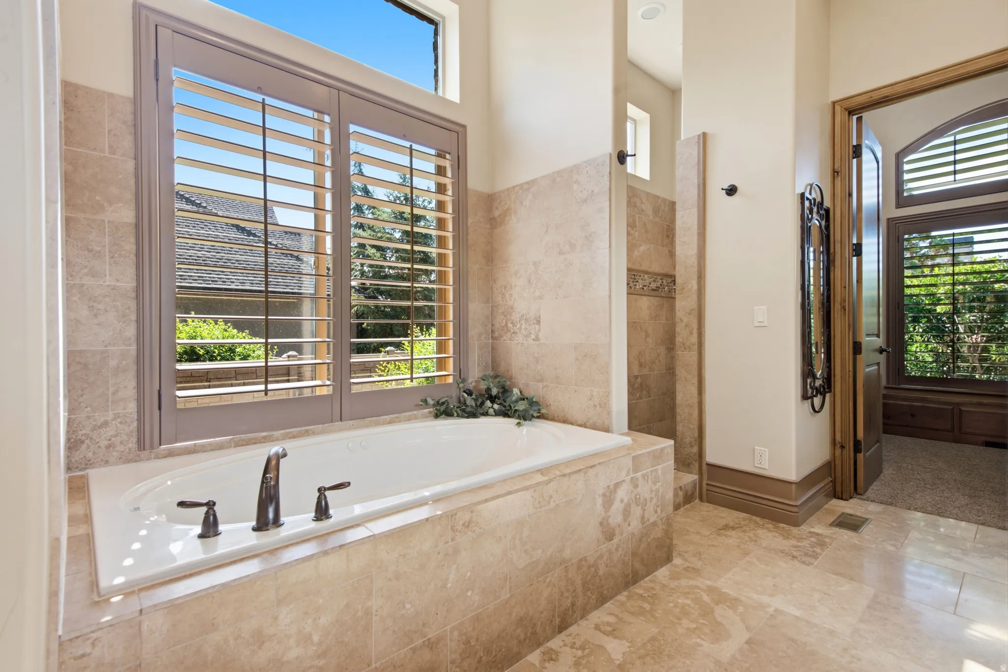 Soaking tub with bronze fixtures, surrounded by stone tile