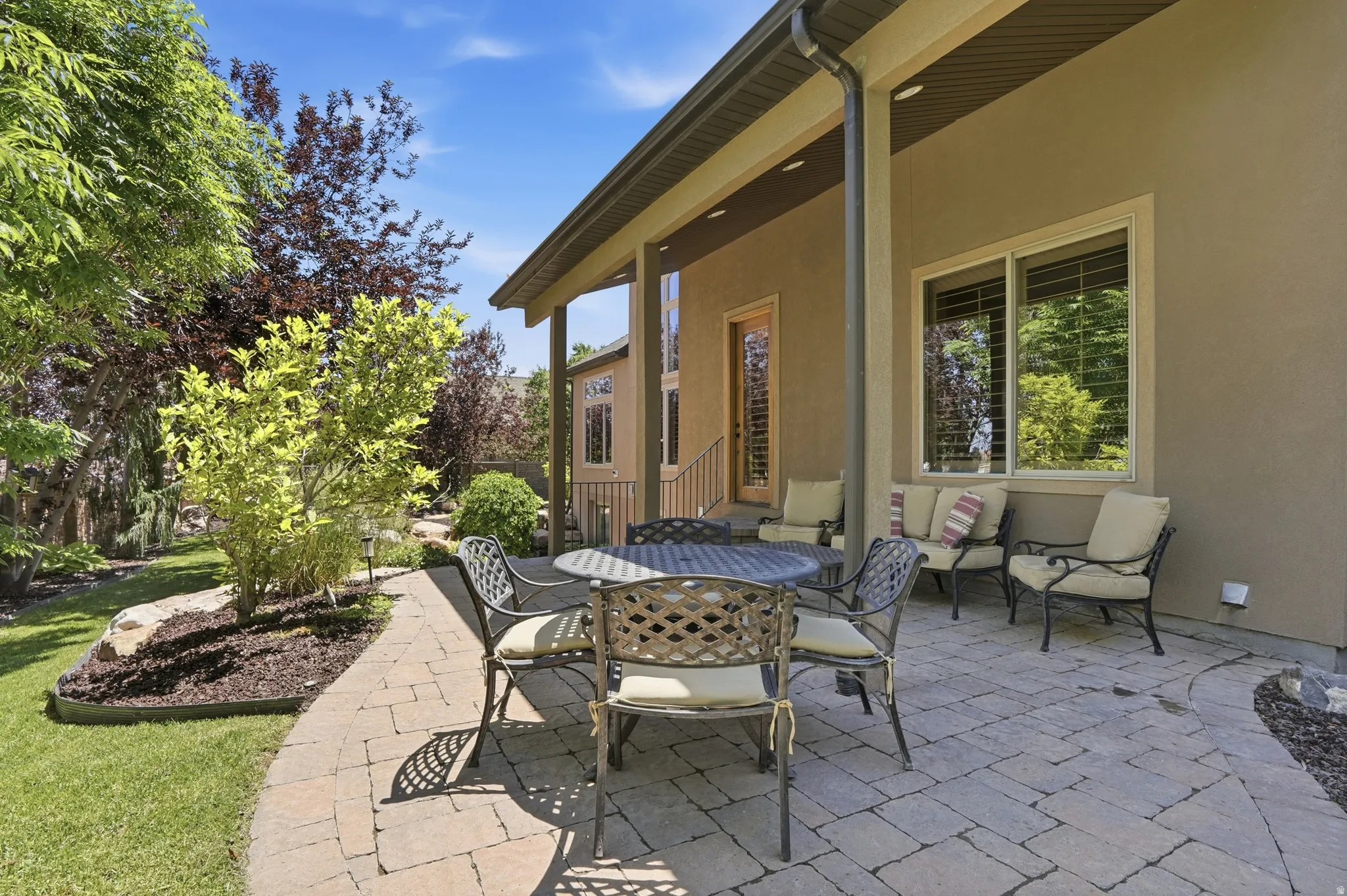 Expansive covered patio featuring paver stone flooring, stucco exterior, and multiple windows